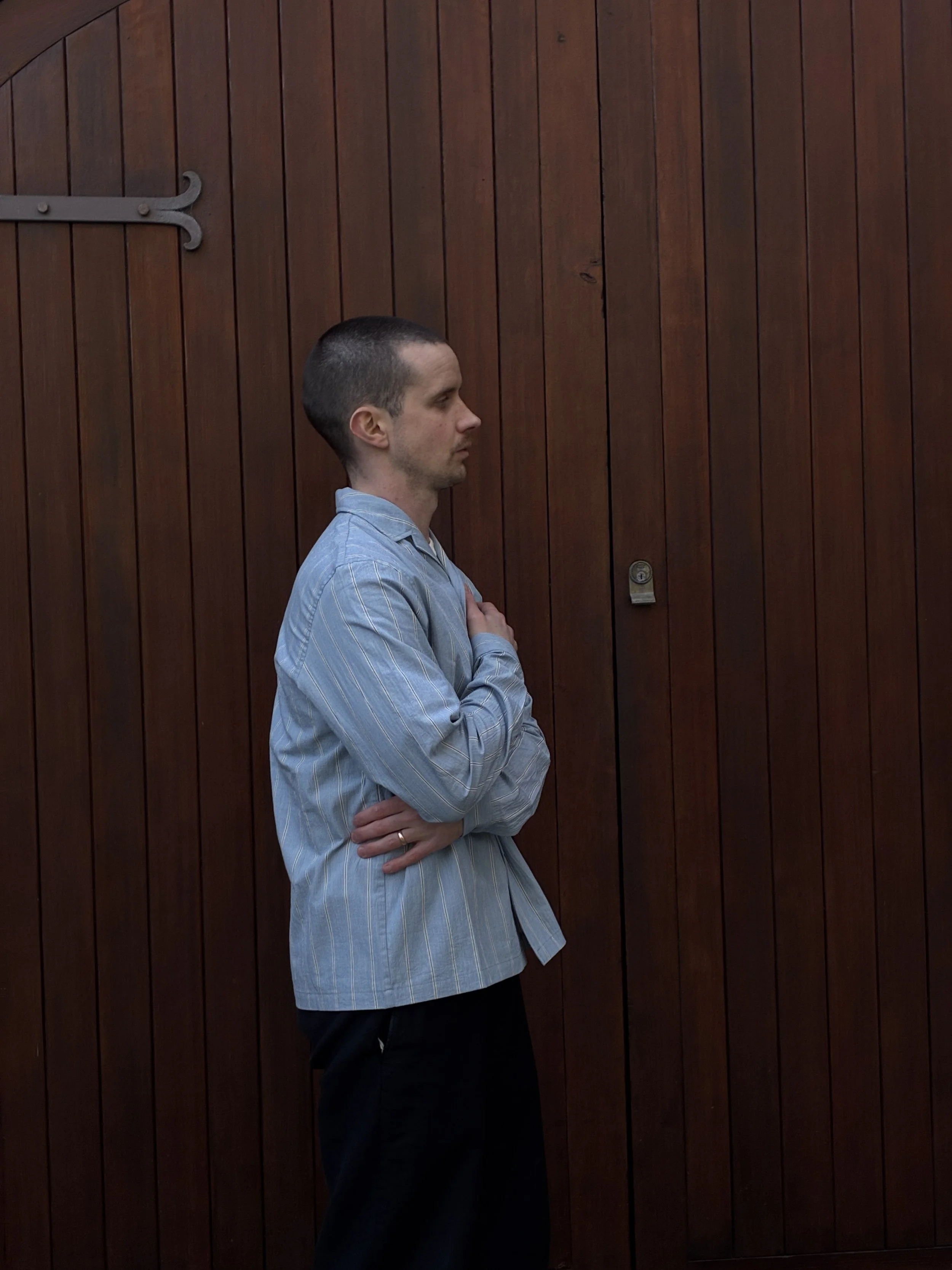 Side of man wearing Frank Leder Japanese Cotton Blue Striped Shirt in front of door