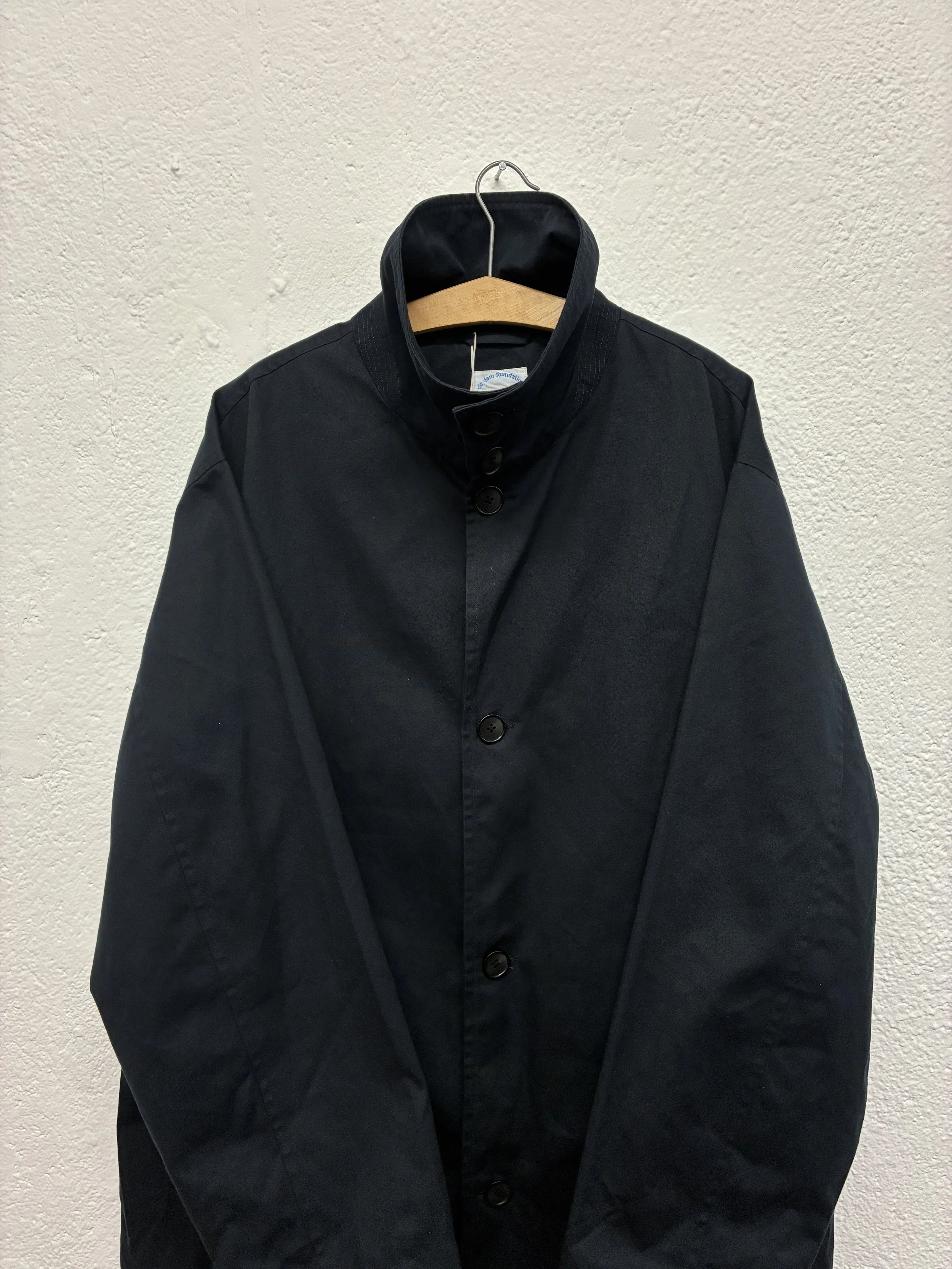 Closeup of Navy De Dam Foundation Cotton Gabardine Trench Coat on hanger