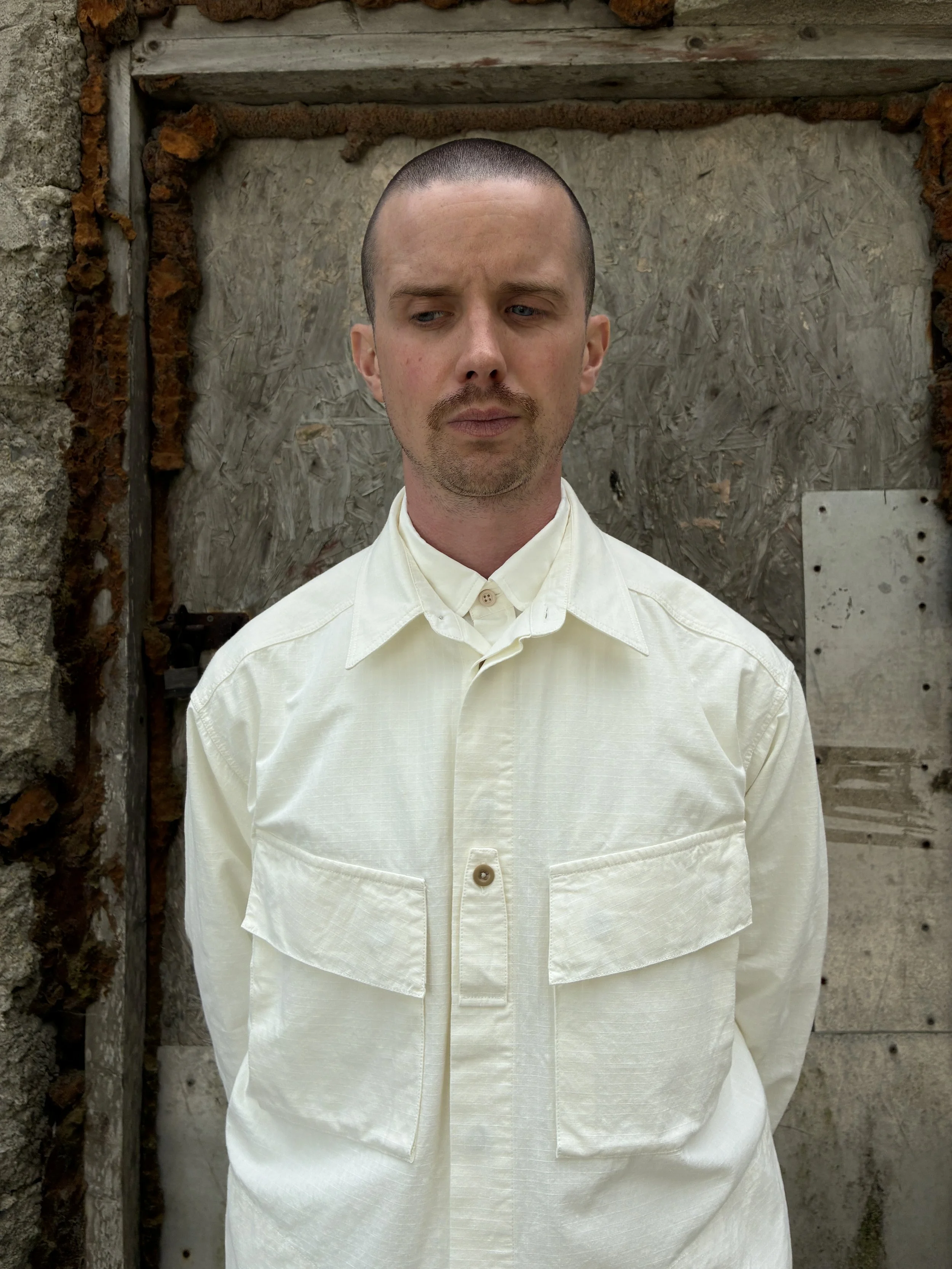 Closeup of Man in front of wall wearing Off-White Ecru 1st PAT-RN Sumatra Overshirt