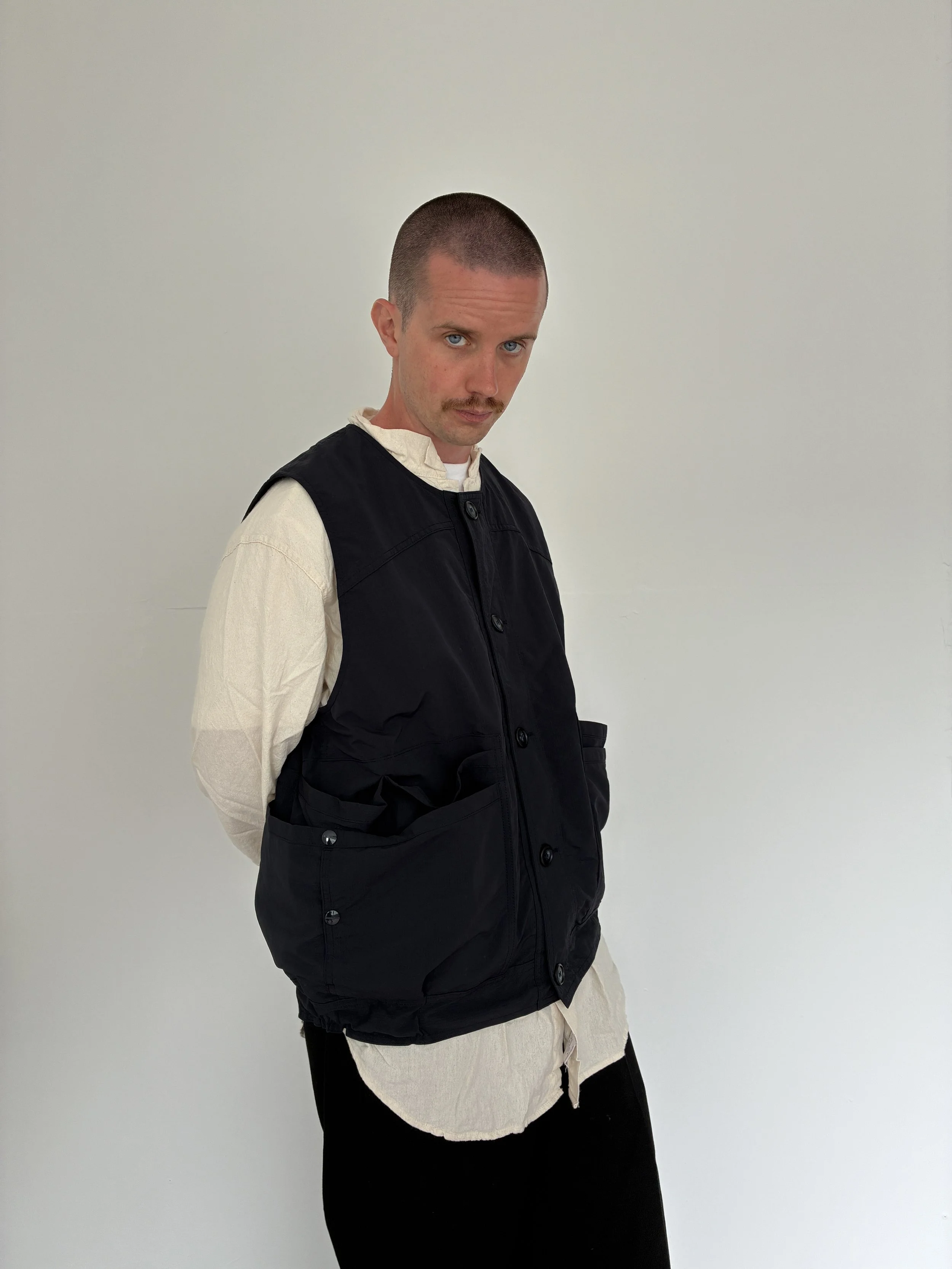 Man wearing Navy Sassafras Overgrown Hiker Vest  in front of concrete wall