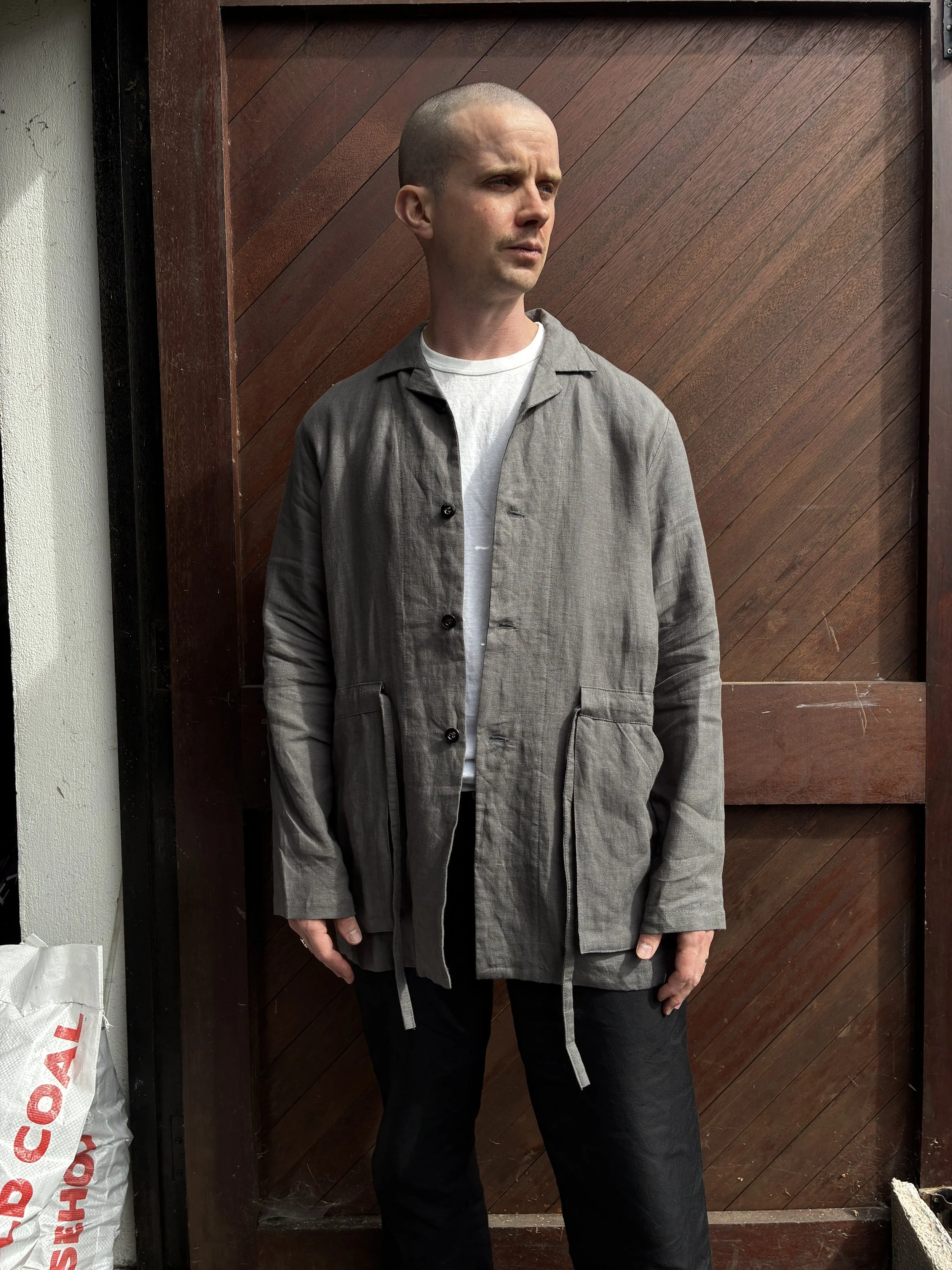 Man in front of wooden door wearing Limited Edition Frank Leder Grey LINDWURM Linen Cardigan over white tshirt