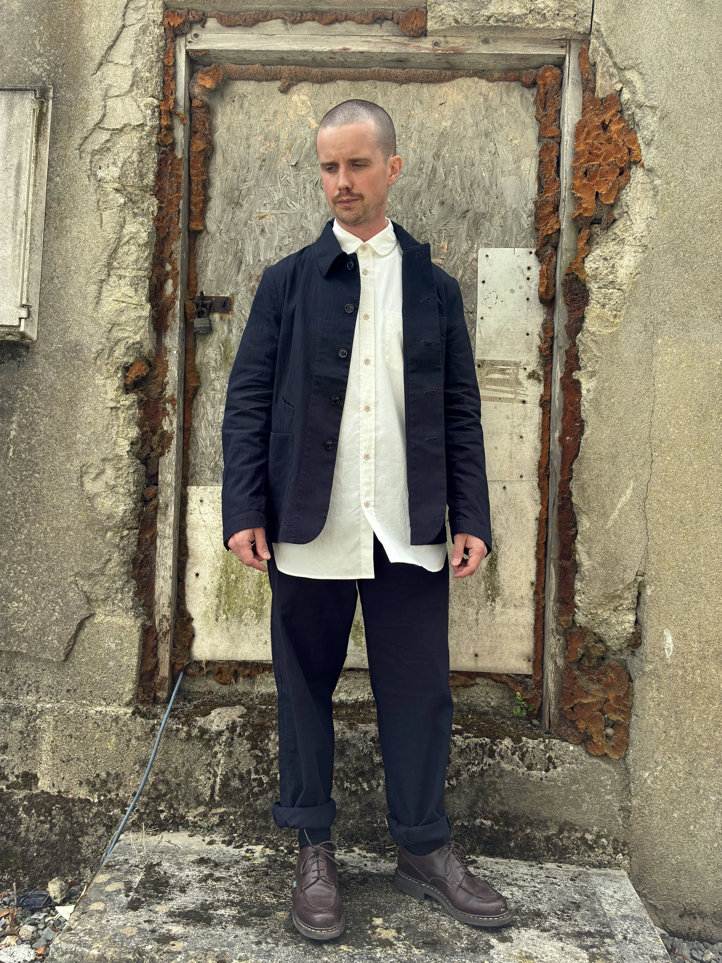 Man in front of wall wearing Navy 1st PAT-RN Notion Jacket unbuttoned