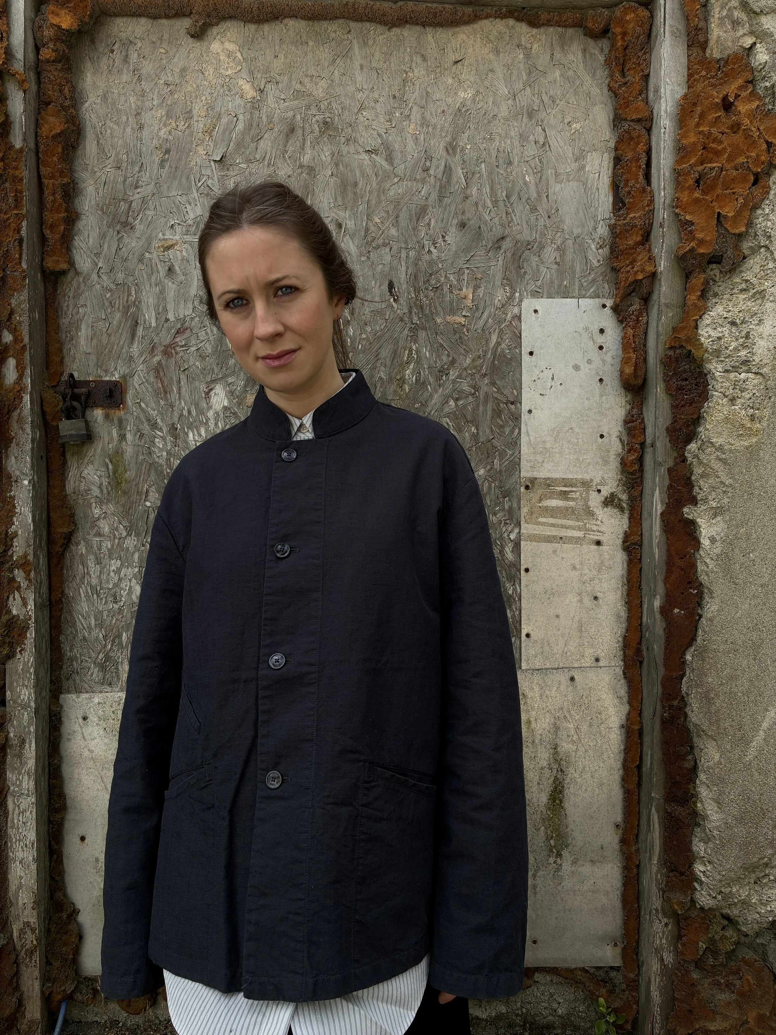 Woman in front of wall wearing Navy 1st PAT-RN Woman Rei Jacket