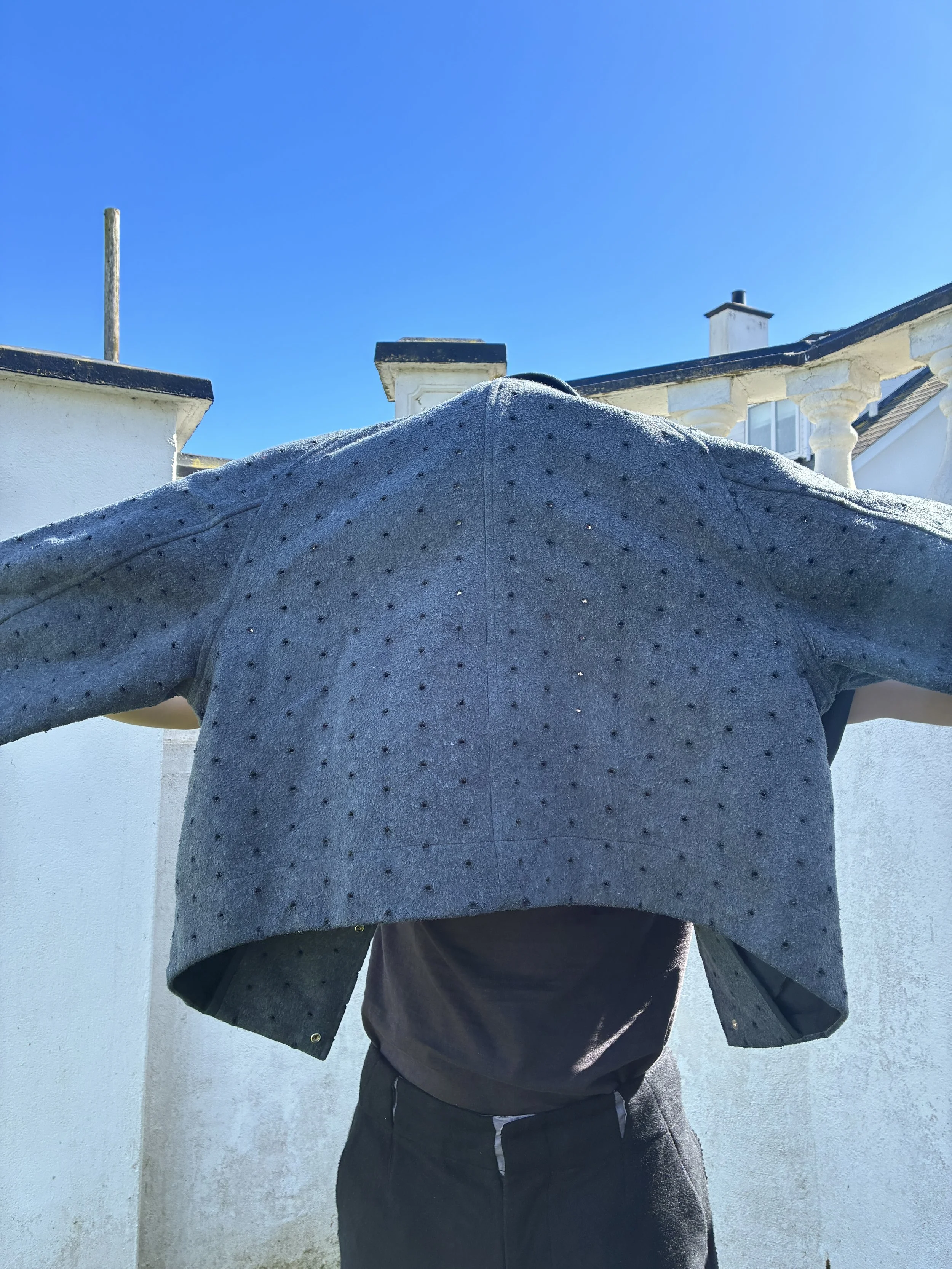 Man holding grey Middle Distance drill jacket over head and up to sky