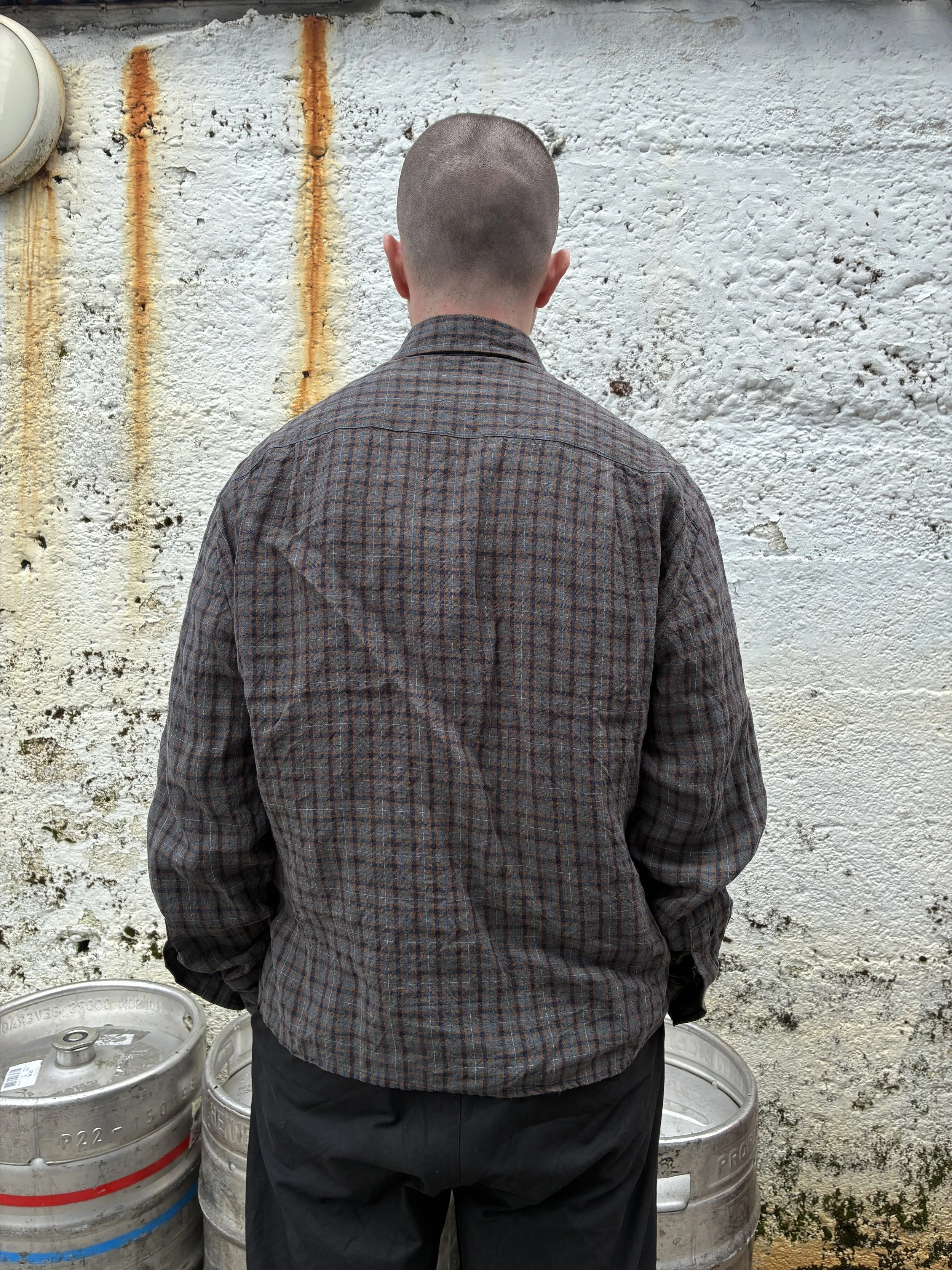 Back of Man wearing Dusk Conkers Relaxed Farmer Shirt beside beer kegs