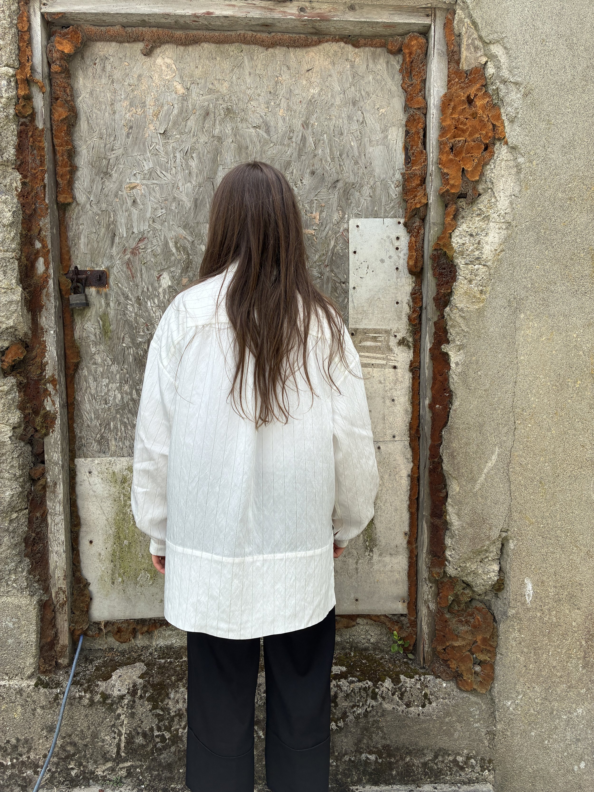 Back of woman in front of wall wearing 1st PAT-RN Woman Modula Shirt in  Tailored Stripes