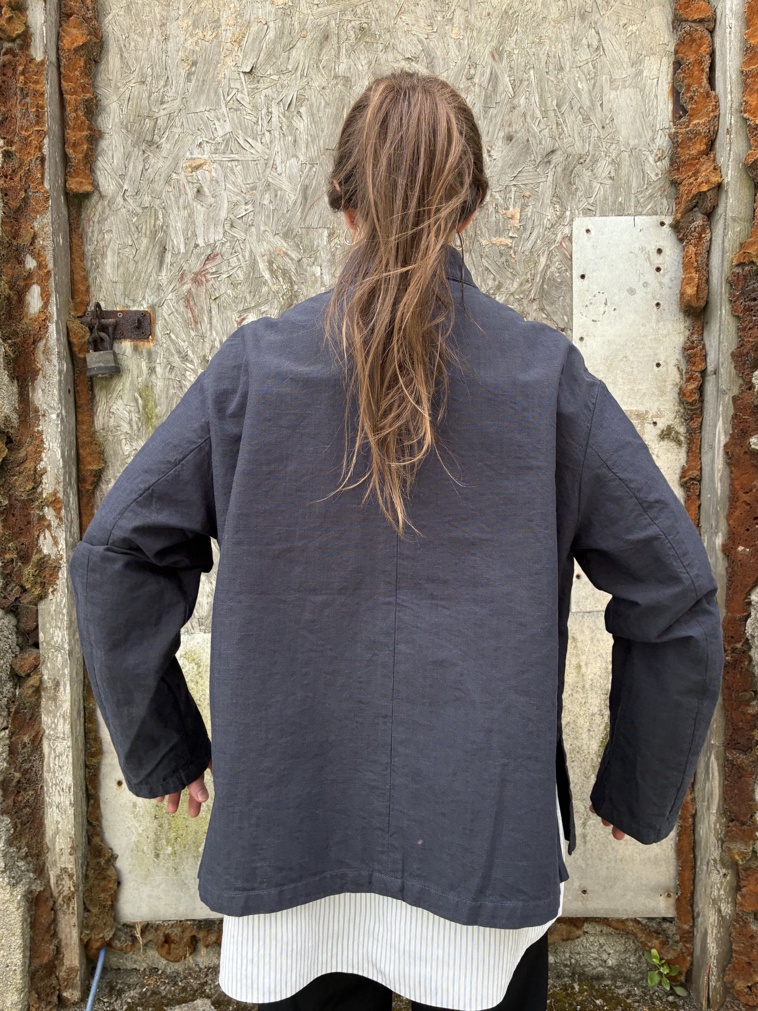 Back of Woman in front of wall wearing Navy 1st PAT-RN Woman Rei Jacket