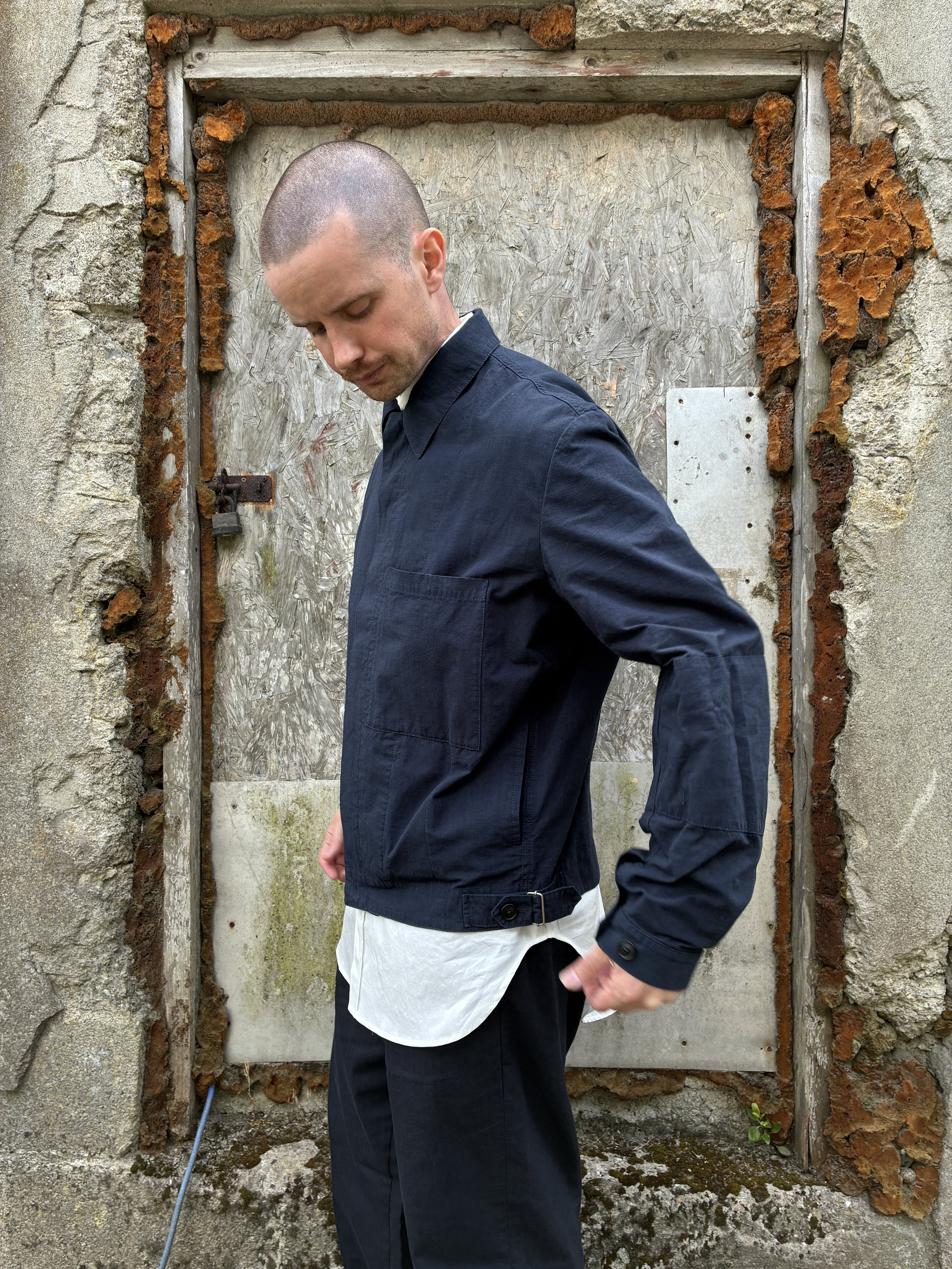 Side of Man in front of wall wearing 1st PAT-RN Navy Camden Jacket
