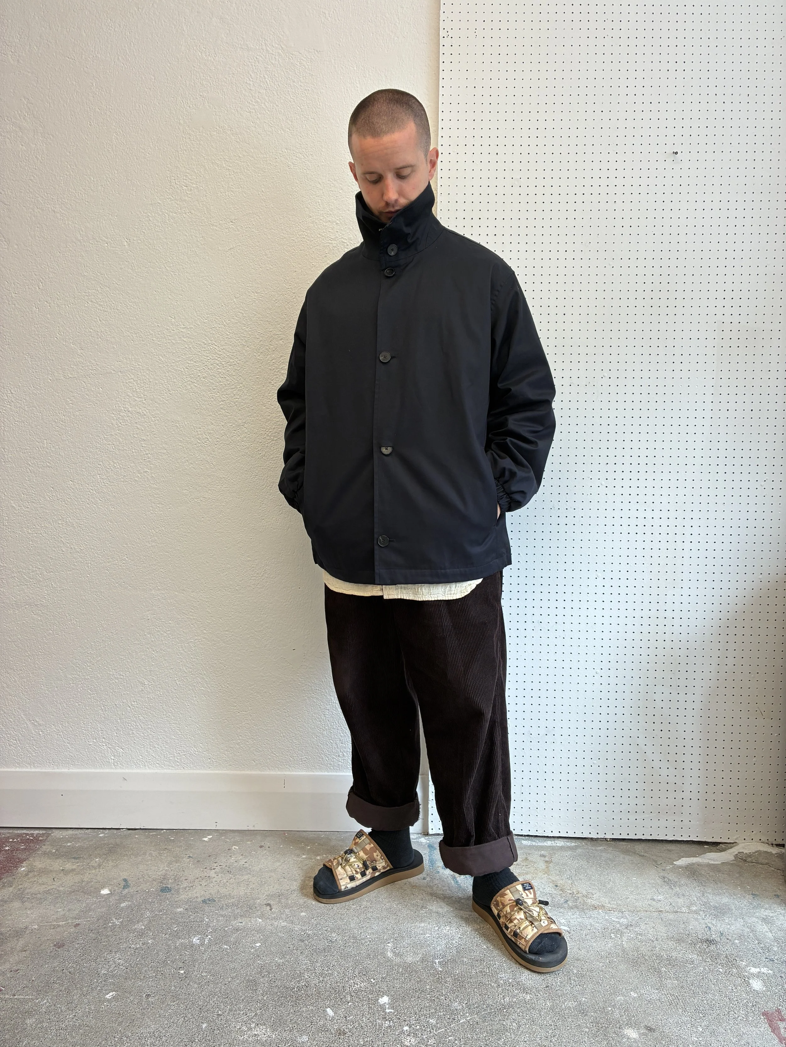 Man wearing Navy De Dam Foundation Cotton Gabardine Jacket buttoned up over face