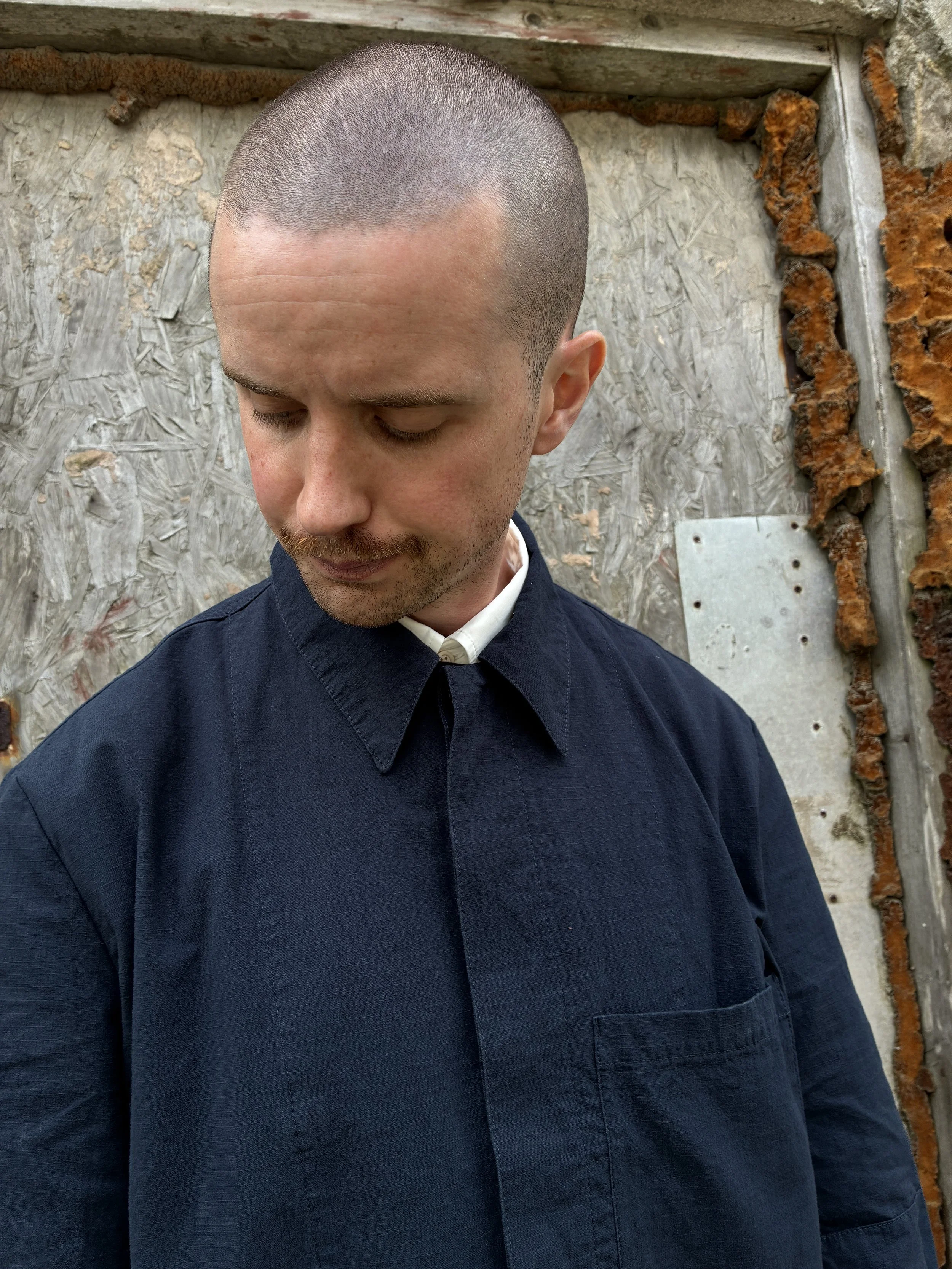 Closeup of Man in front of wall wearing 1st PAT-RN Navy Camden Jacket