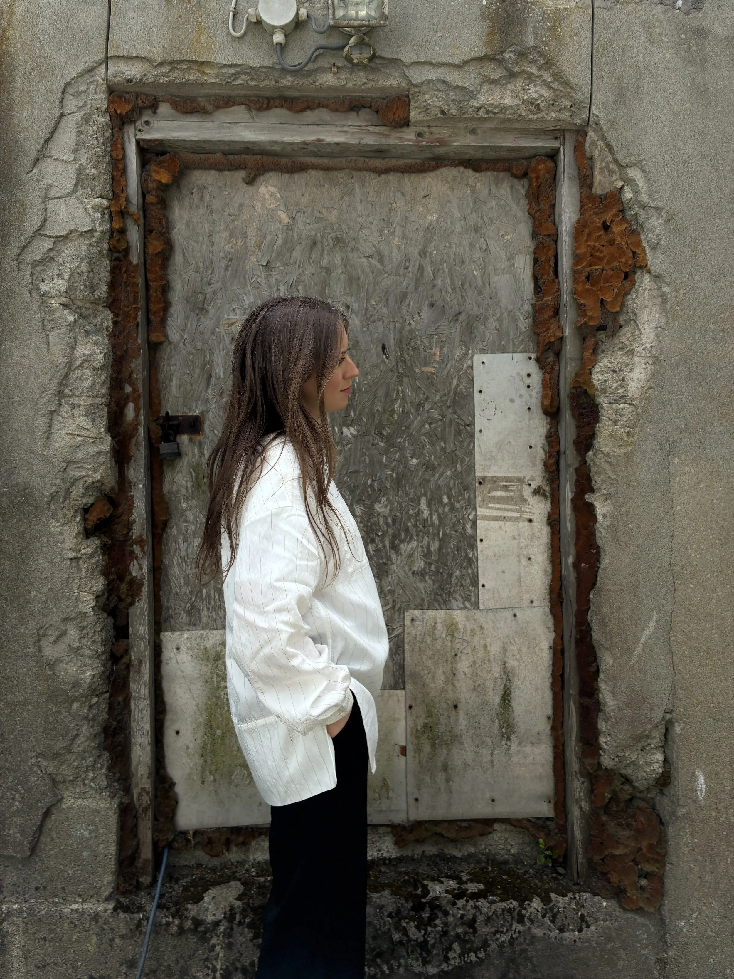 Side of woman in front of wall wearing 1st PAT-RN Woman Modula Shirt in Tailored Stripes with hands in pockets