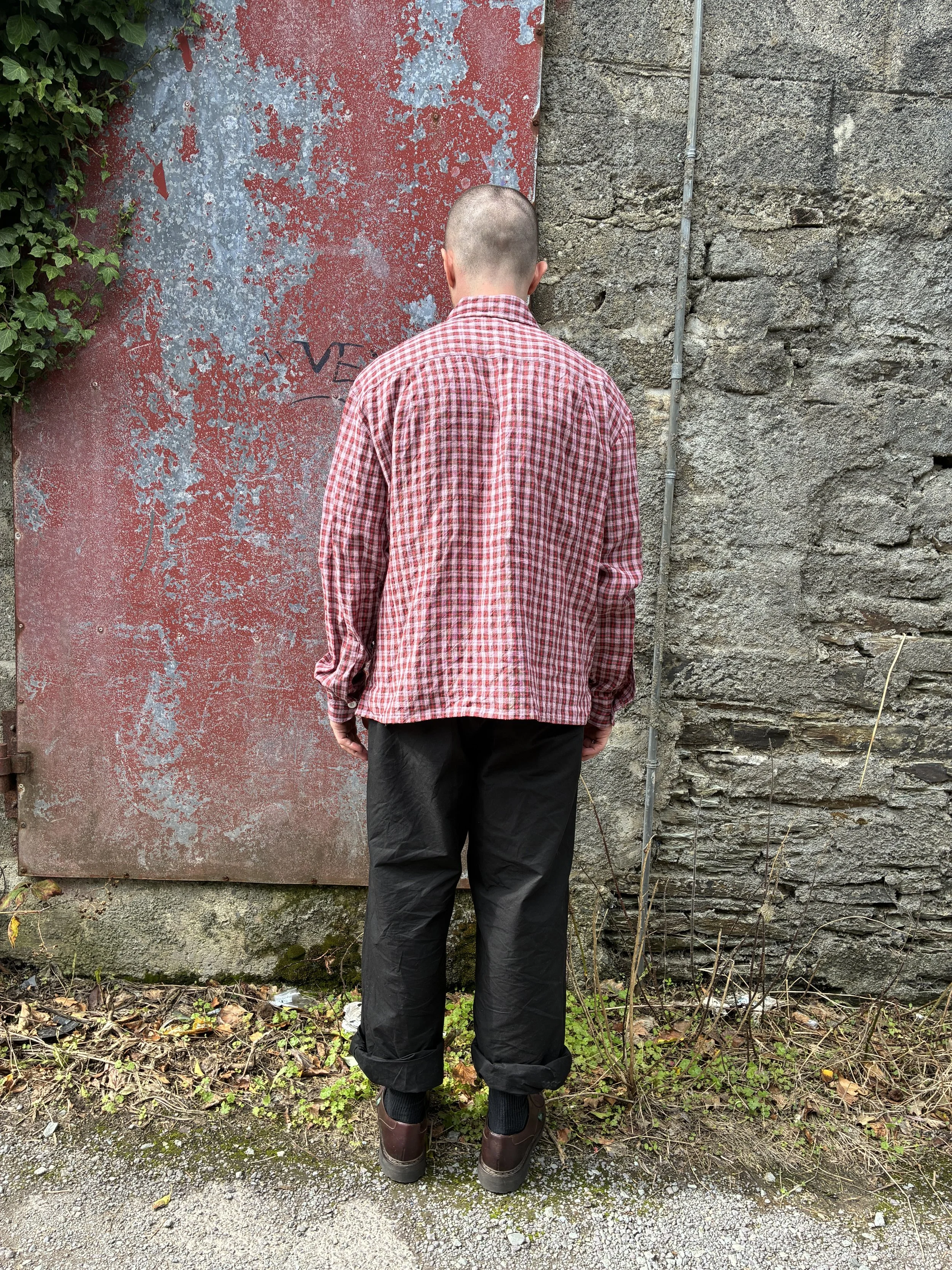 Back of Man wearing Conkers Sunrise Relaxed Farmer Shirt in front of red wall