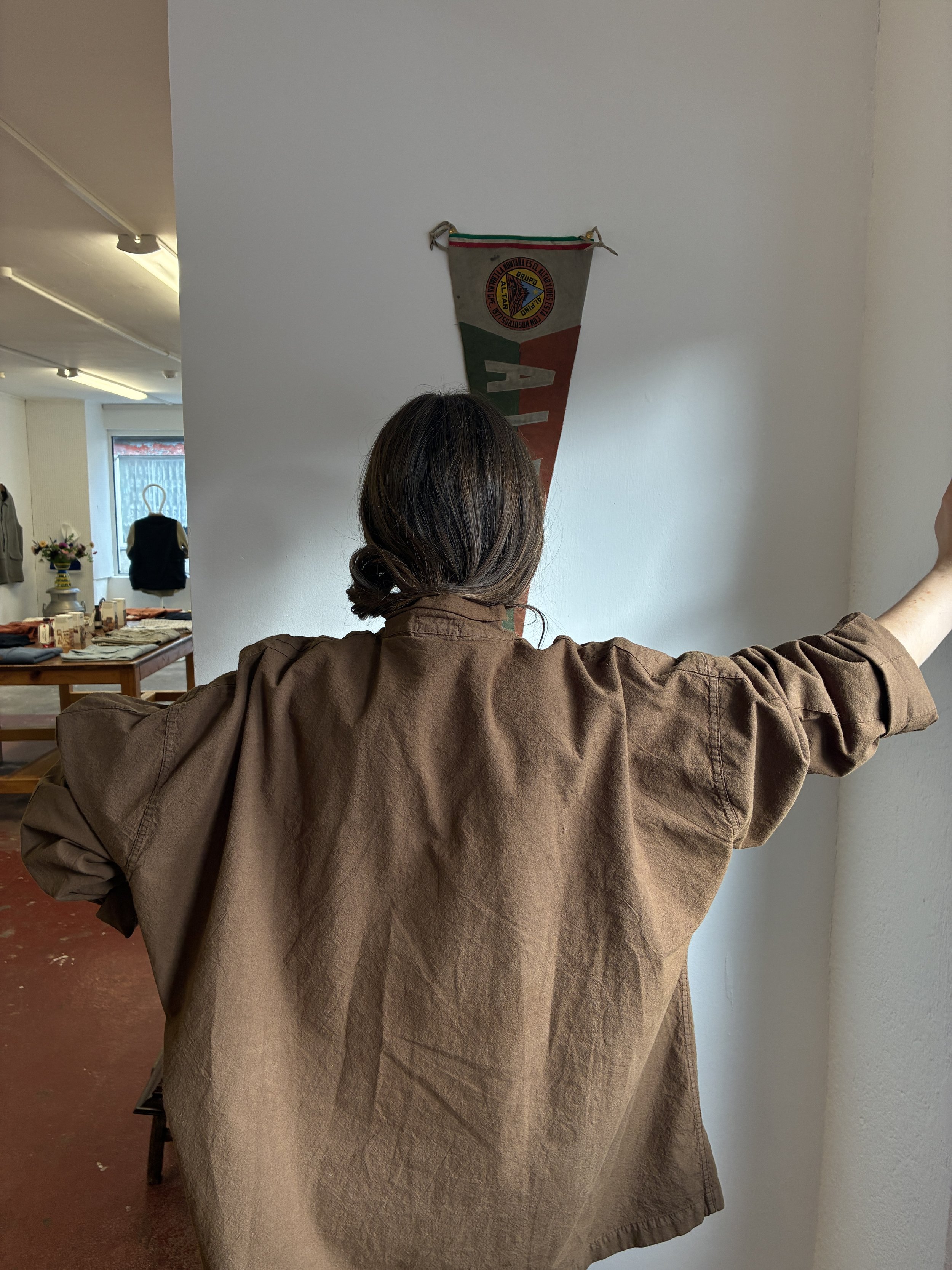 Back of woman leaning against wall wearing Tender Co Type 485 Isosceles Brown Hat Shirt