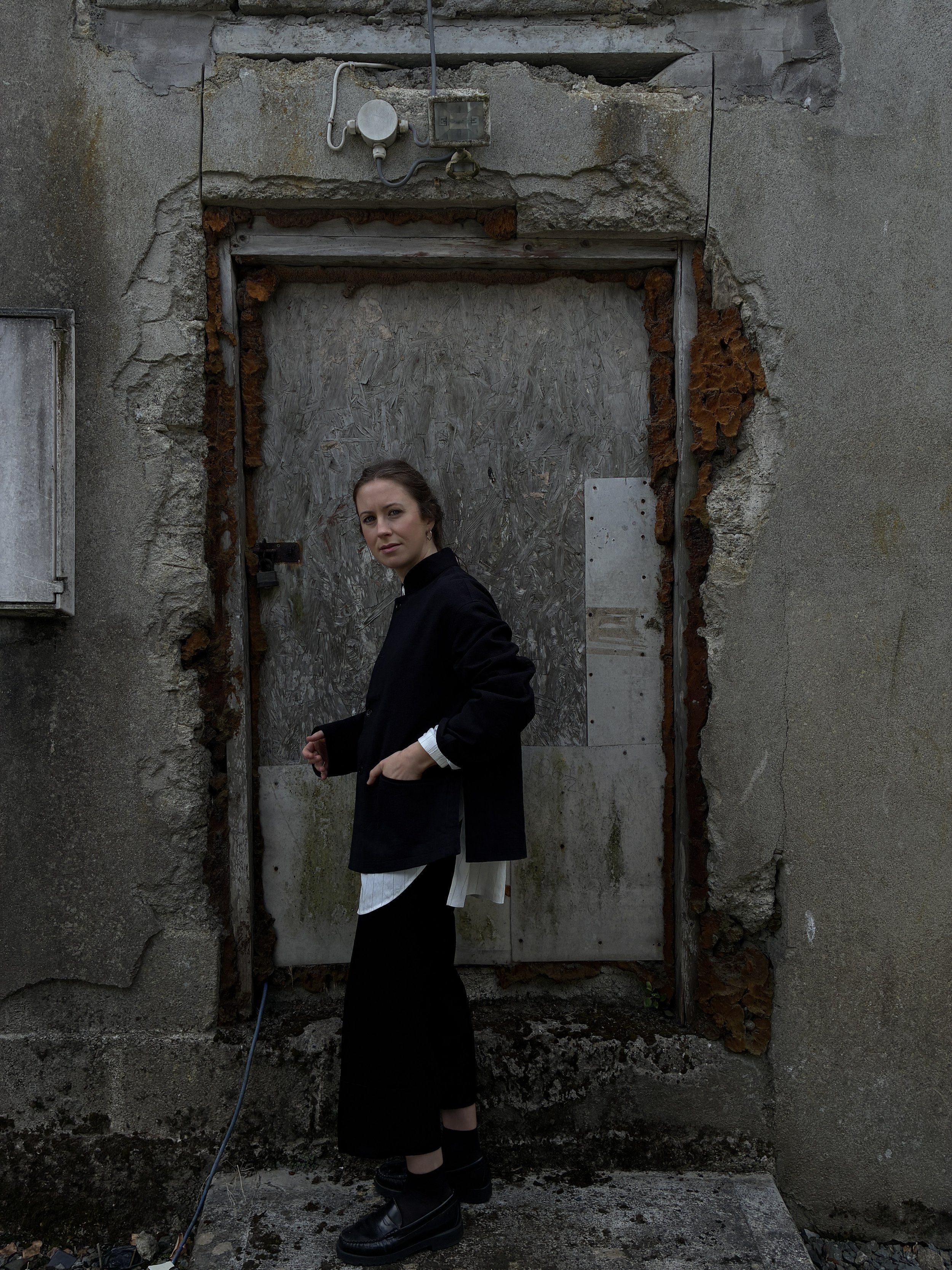 Side of Woman in front of wall wearing Charcoal 1st PAT-RN Woman Rei Jacket