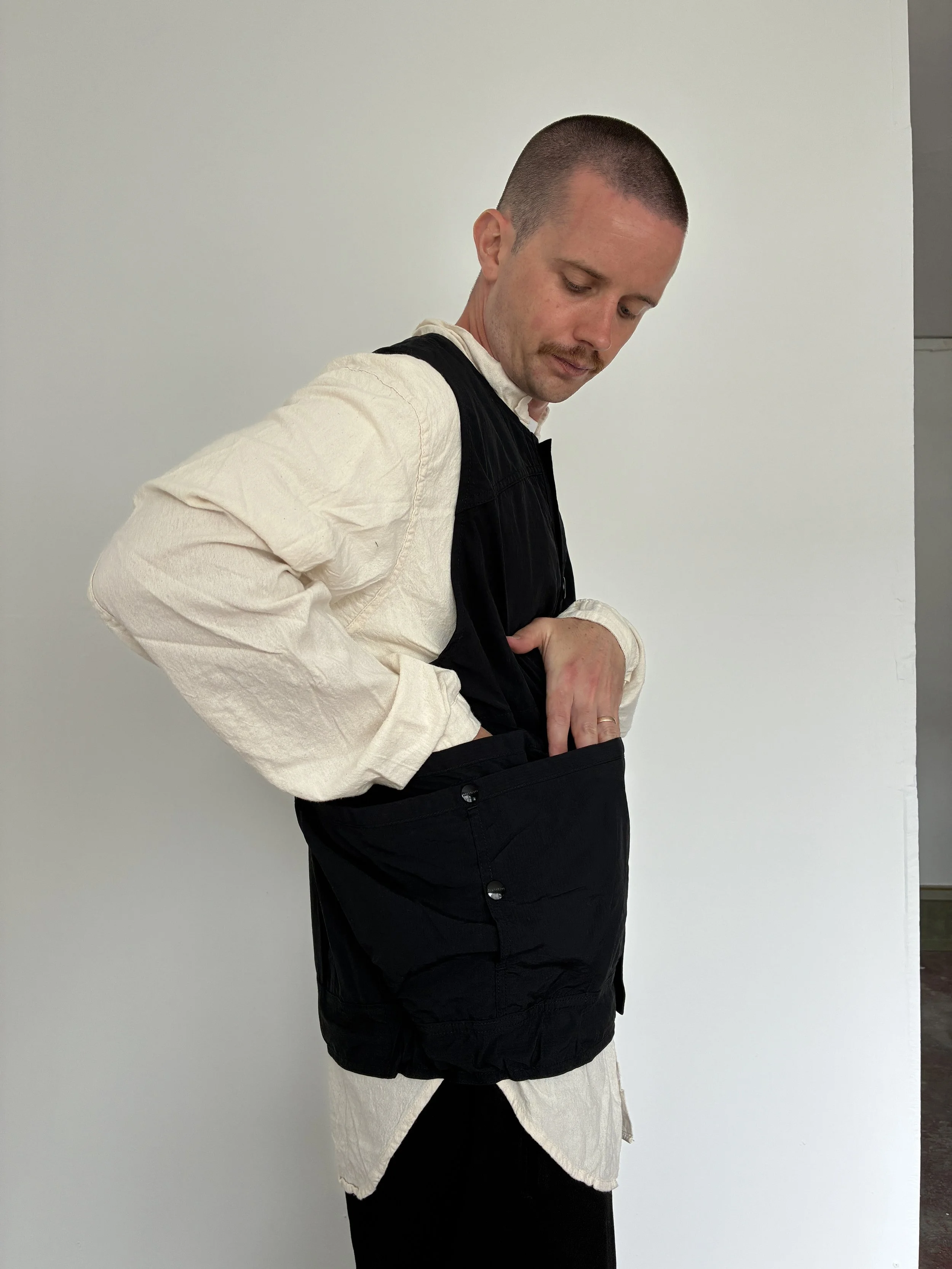 Man looking in pocket of Black Sassafras Overgrown Hiker Vest