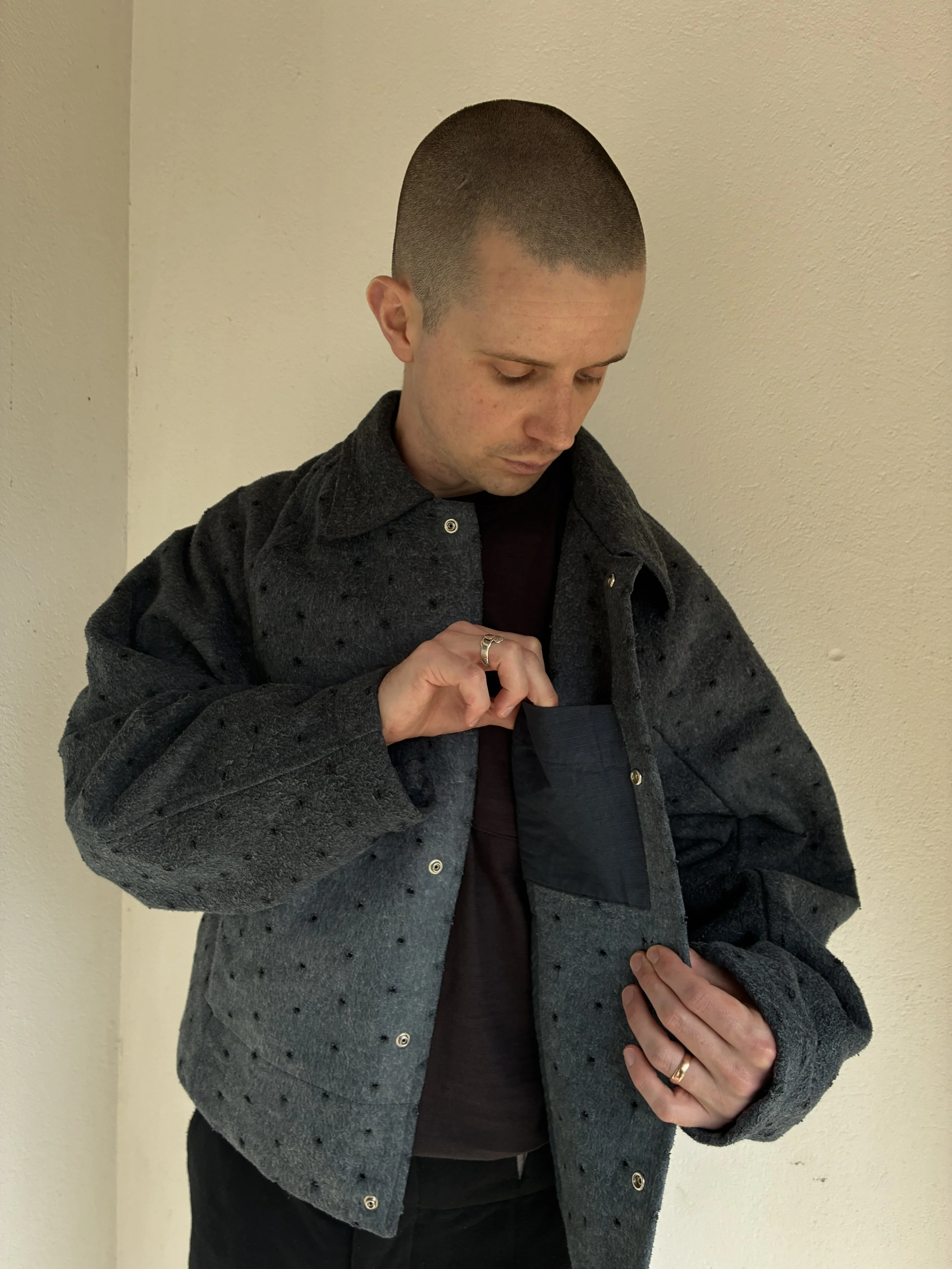 Man looking inside pocket of Middle Distance grey Drill jacket