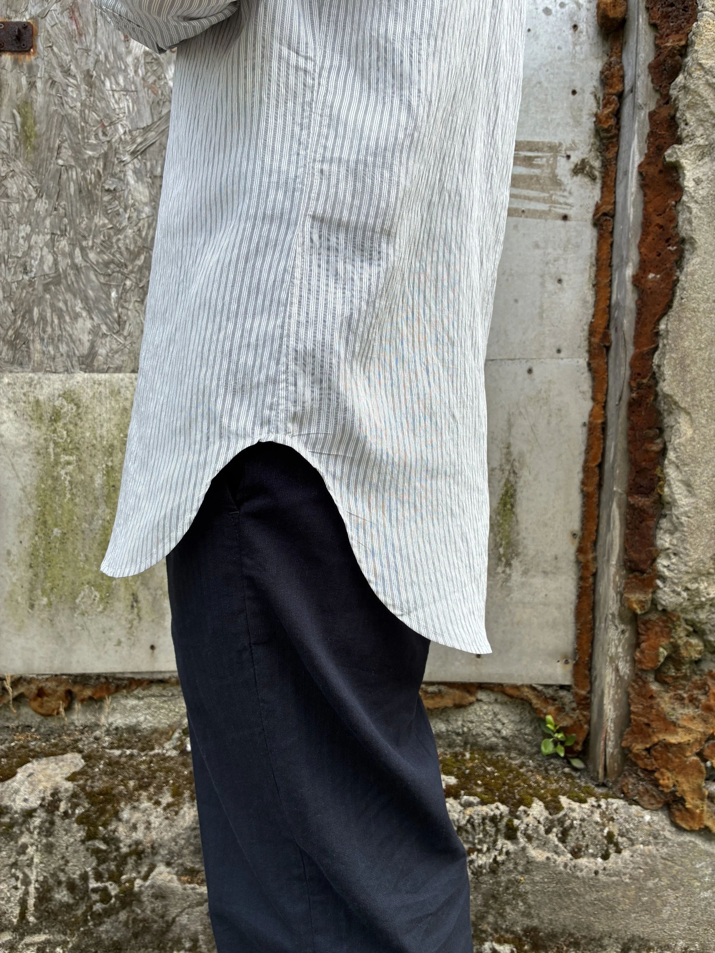 Side view of hem of 1st PAT-RN Boston Shirt in Fine Stripes worn on man in front of wall