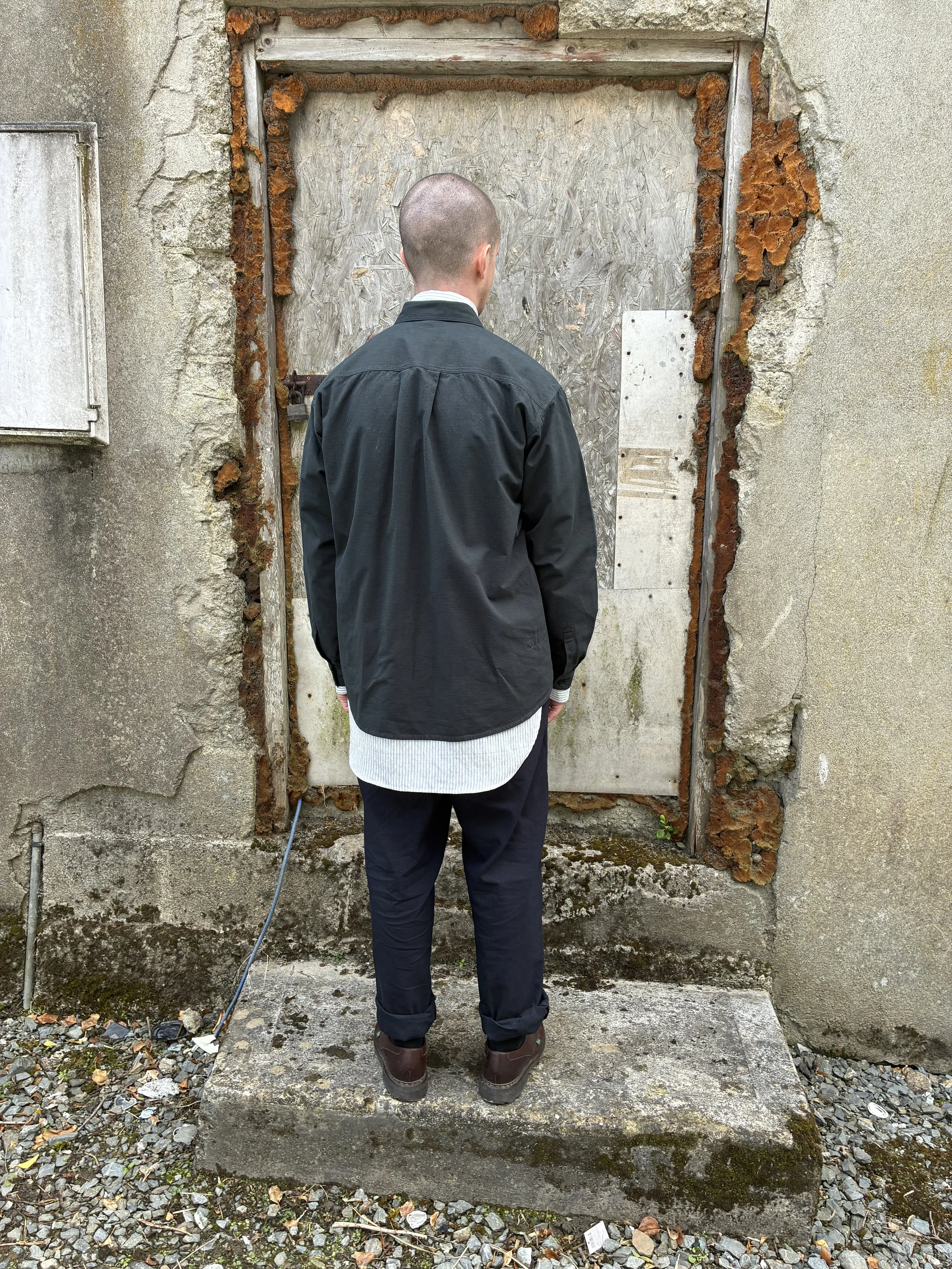 Back of Man in front of wall wearing 1st PAT-RN Sumatra Charcoal Overshirt