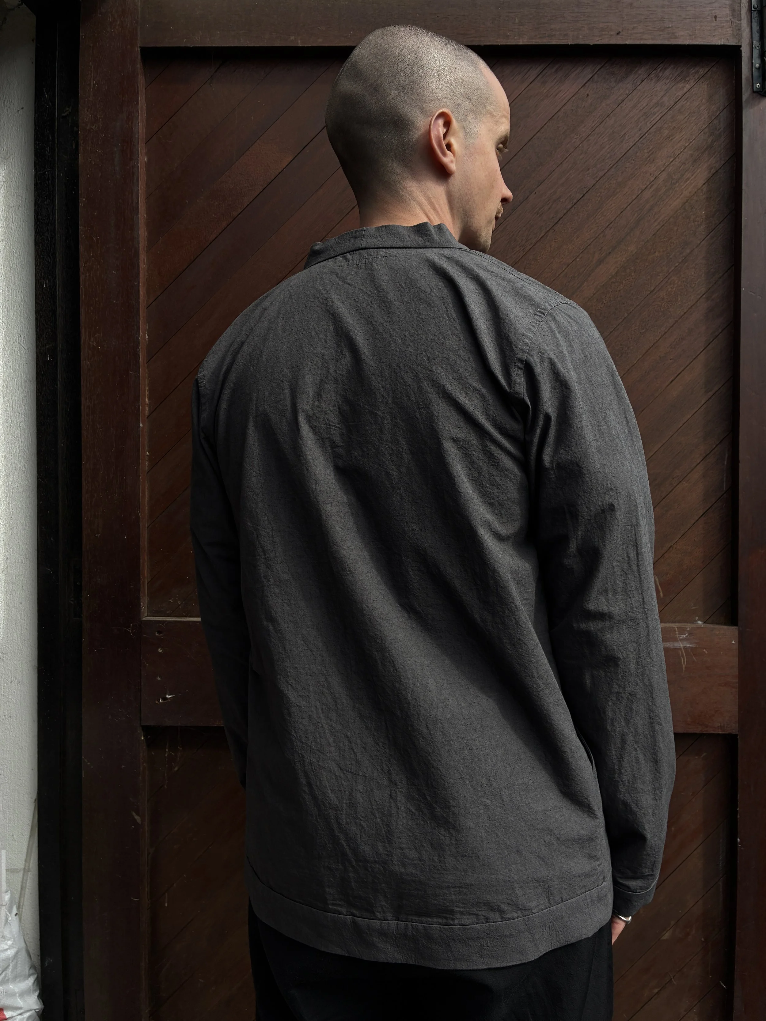 Back of man in front of wooden door wearing Frank Leder Grey Japanese Cotton Cardigan