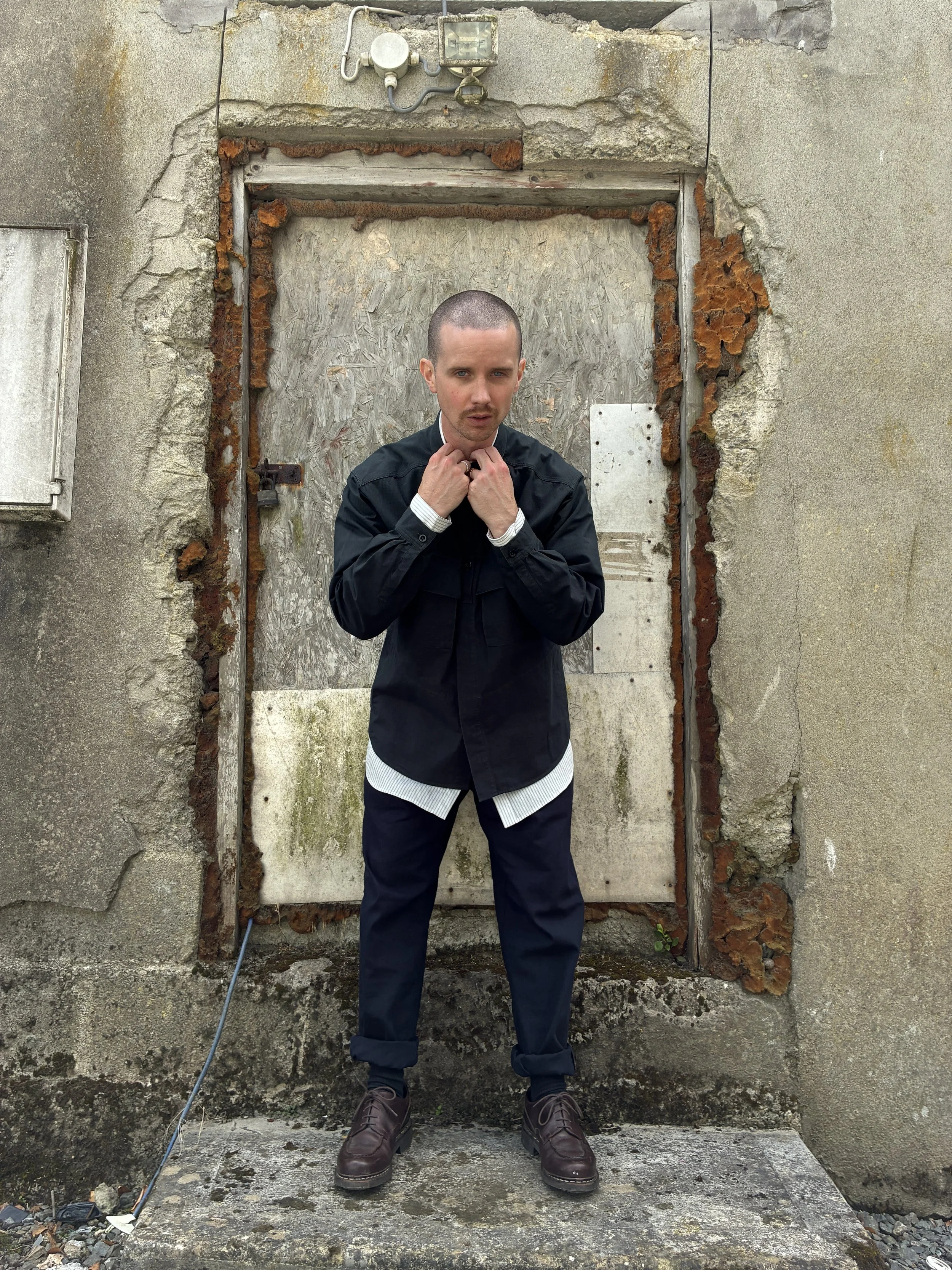 Man in front of wall wearing 1st PAT-RN Sumatra Charcoal Overshirt