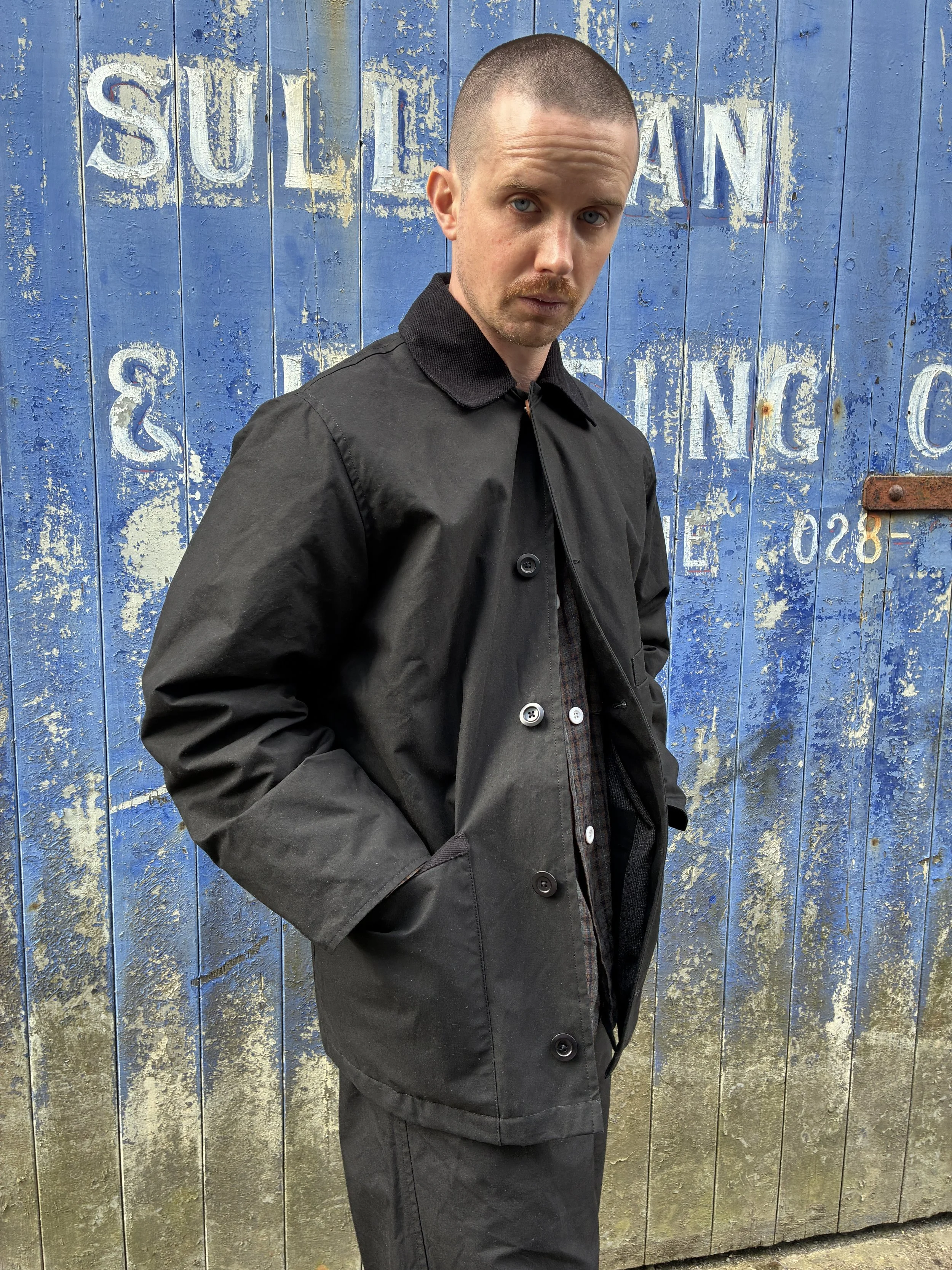 Man wearing Black Conkers Blanket Jacket in front of blue graffiti