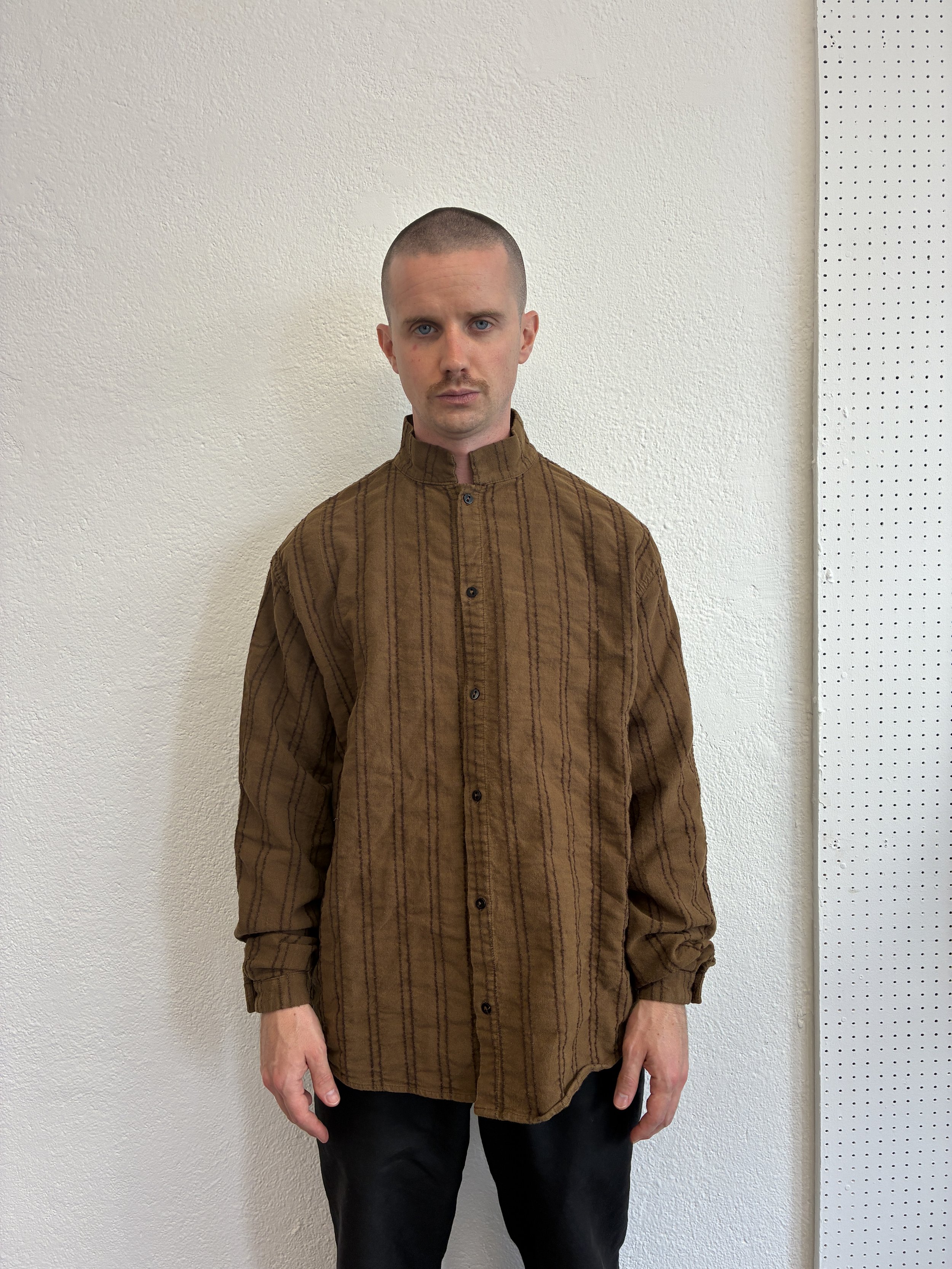 Closeup of back of man wearing Brown Tender Co Type 486 Burro Shirt in front of wall