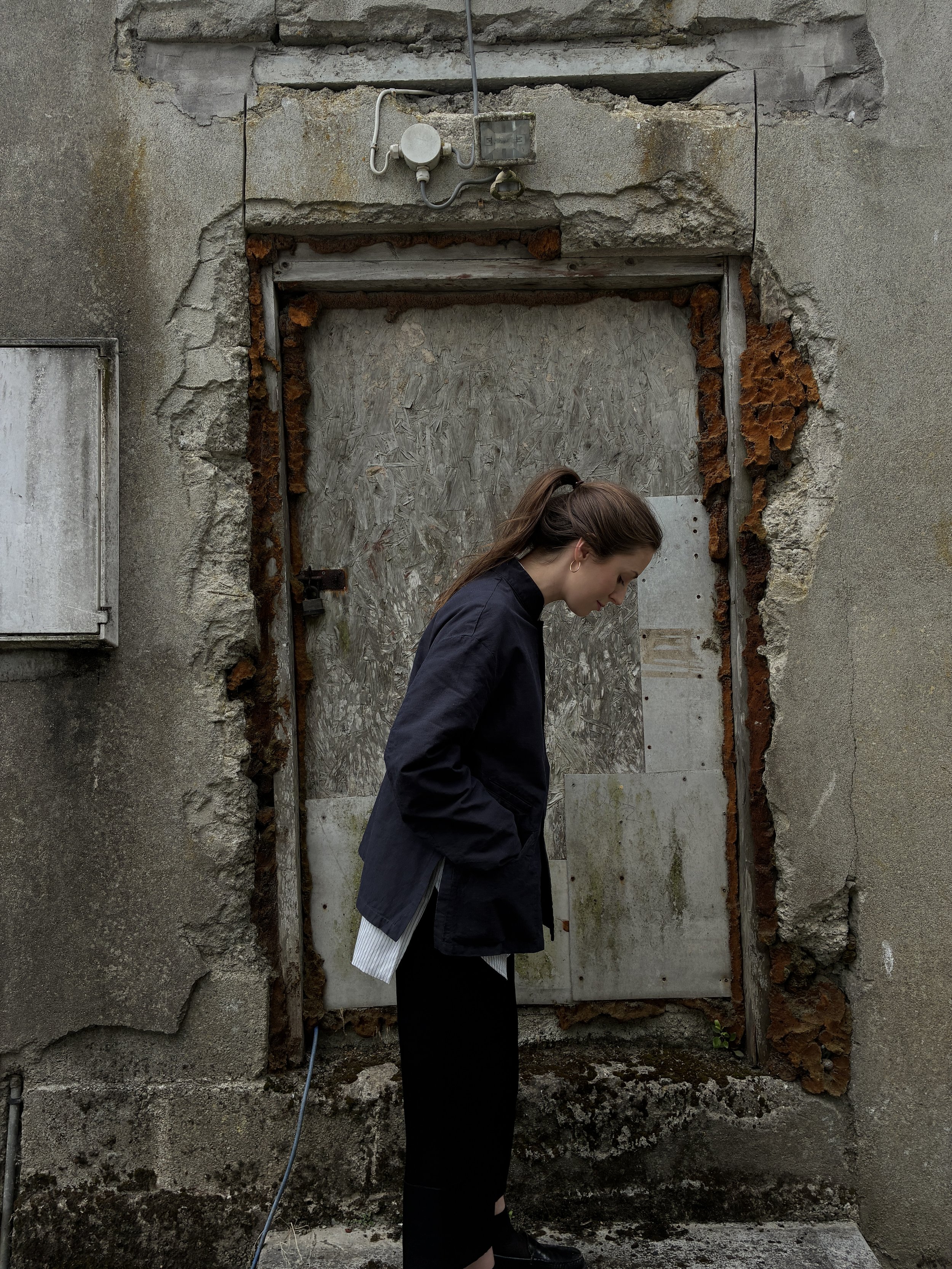 Side of Woman in front of wall wearing Navy 1st PAT-RN Woman Rei Jacket