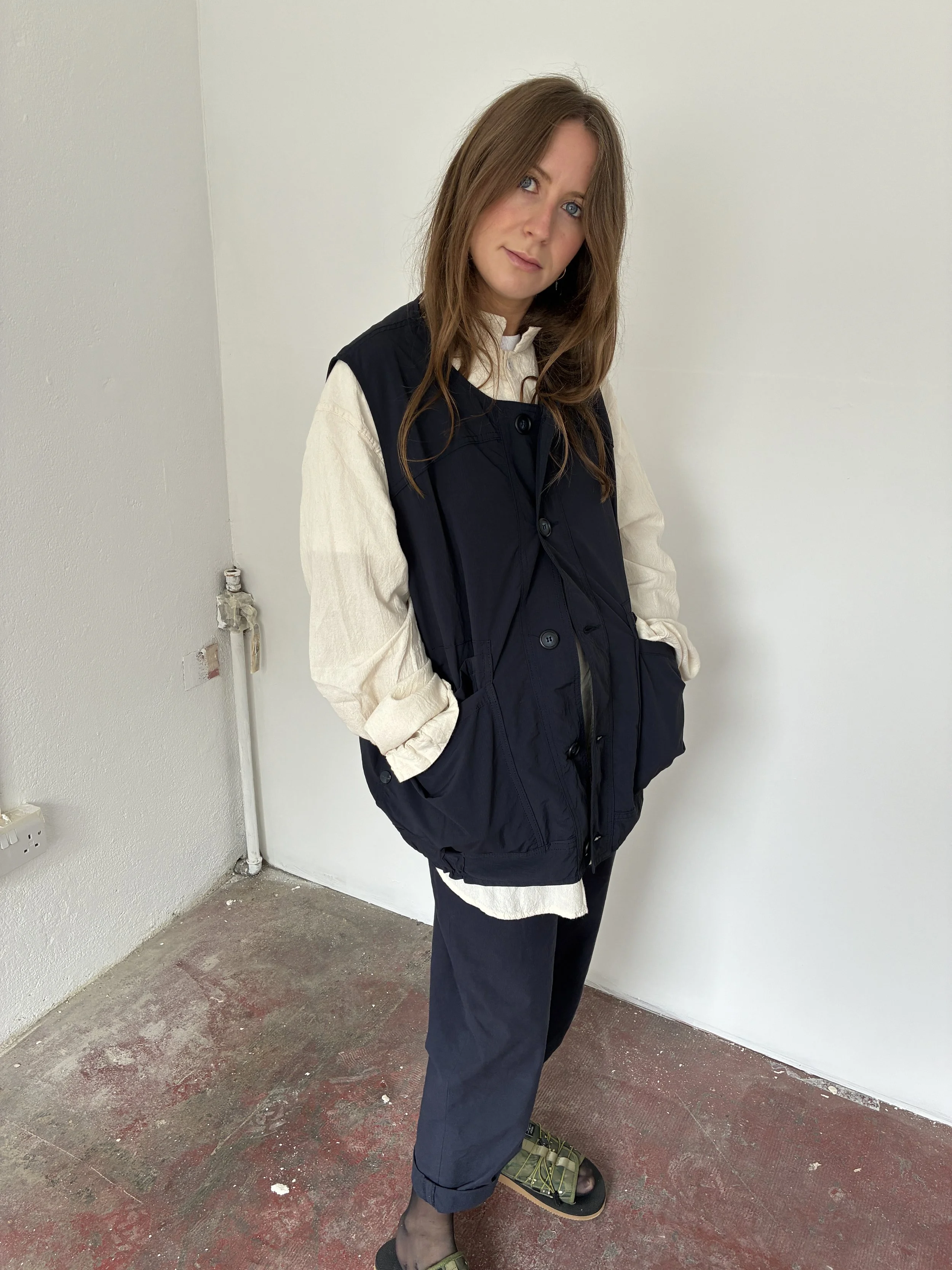 Woman wearing Navy Sassafras Overgrown Hiker Vest in front of concrete wall
