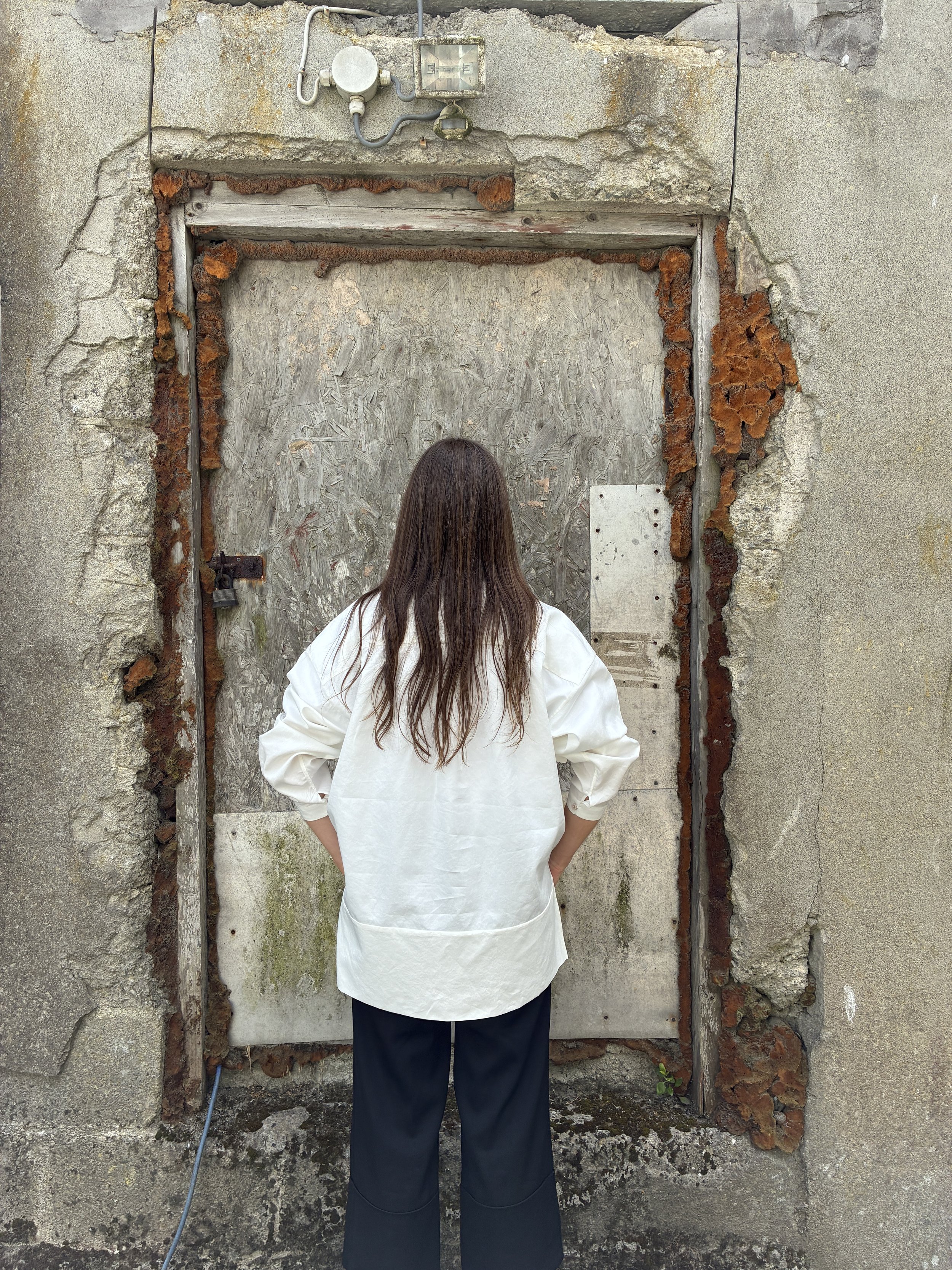 Back of Woman in front of wall wearing White 1st PAT-RN Woman Modula Shirt
