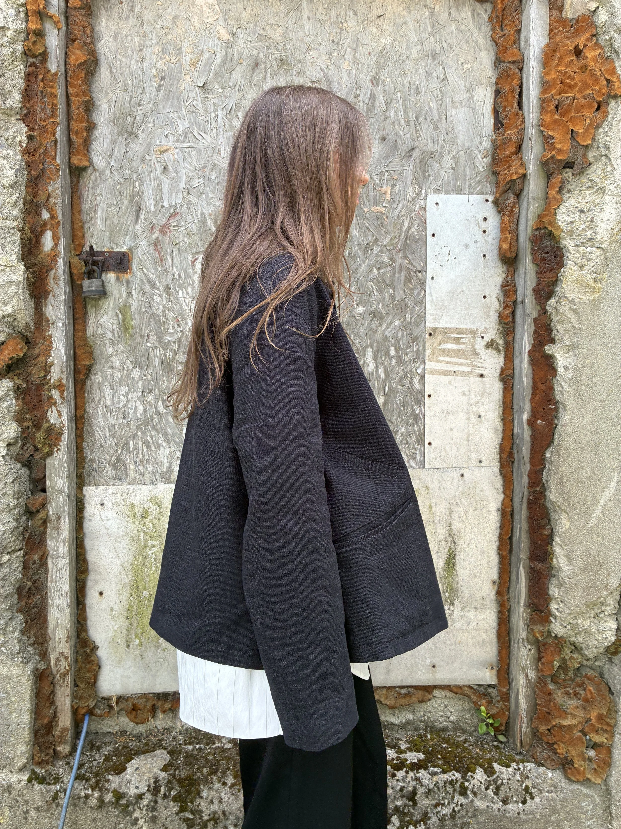 Side of woman in front of wall wearing Charcoal 1st PAT-RN Woman Rei Jacket
