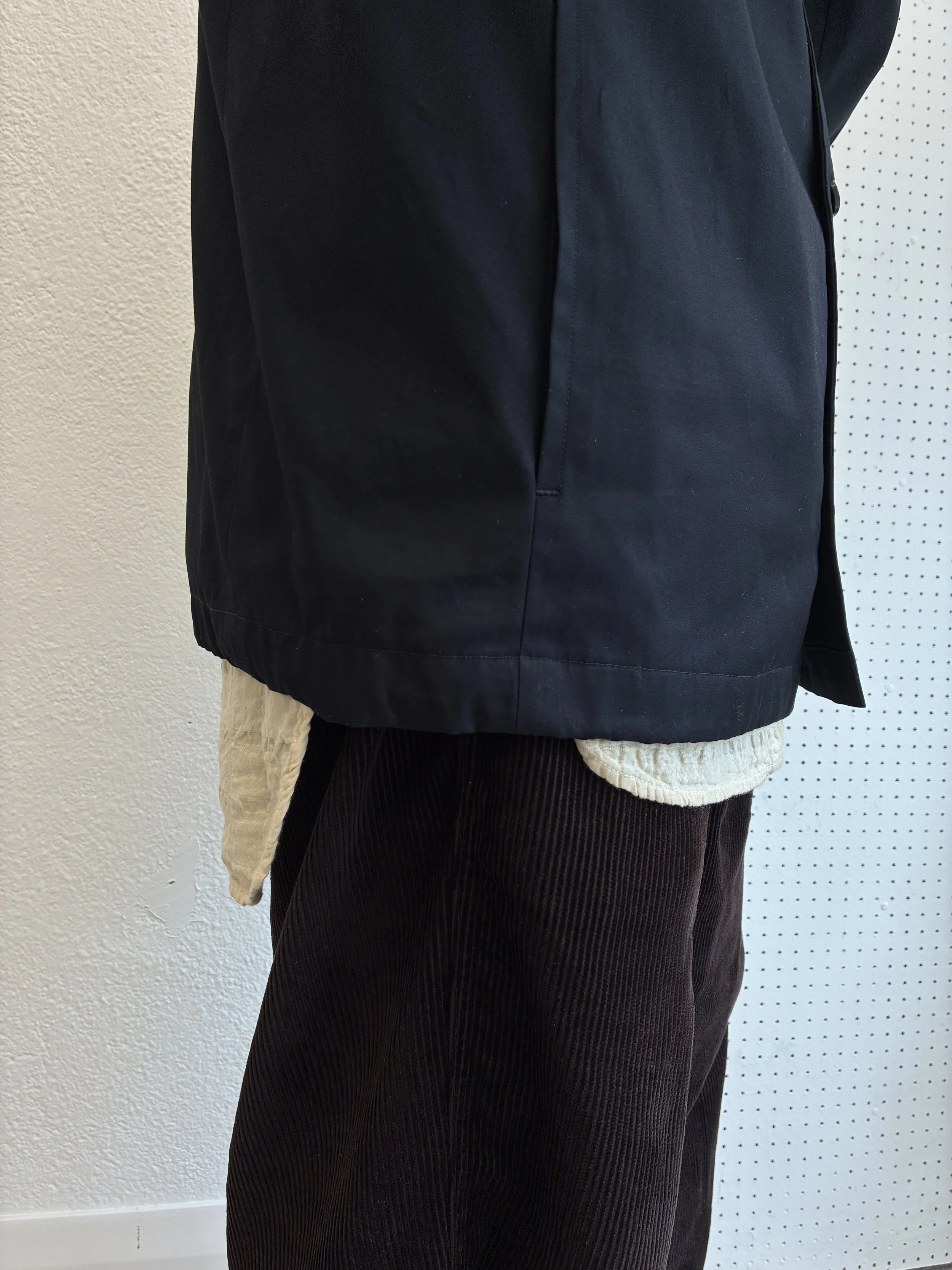 Closeup of Navy De Dam Foundation Cotton Gabardine Jacket over cream shirt tail and brown cords