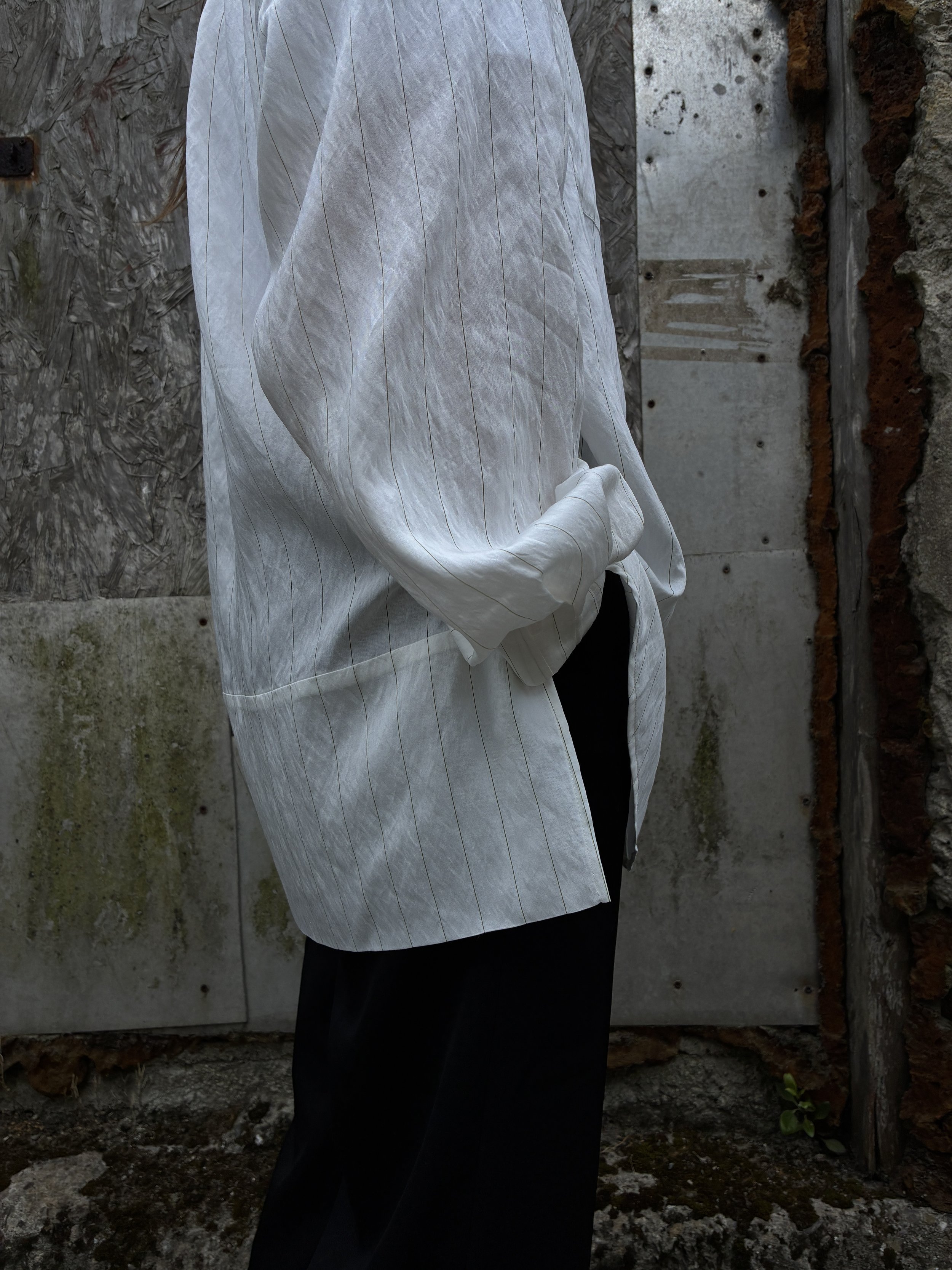 Side closeup of woman in front of wall wearing 1st PAT-RN Woman Modula Shirt in  Tailored Stripes with hands in pockets