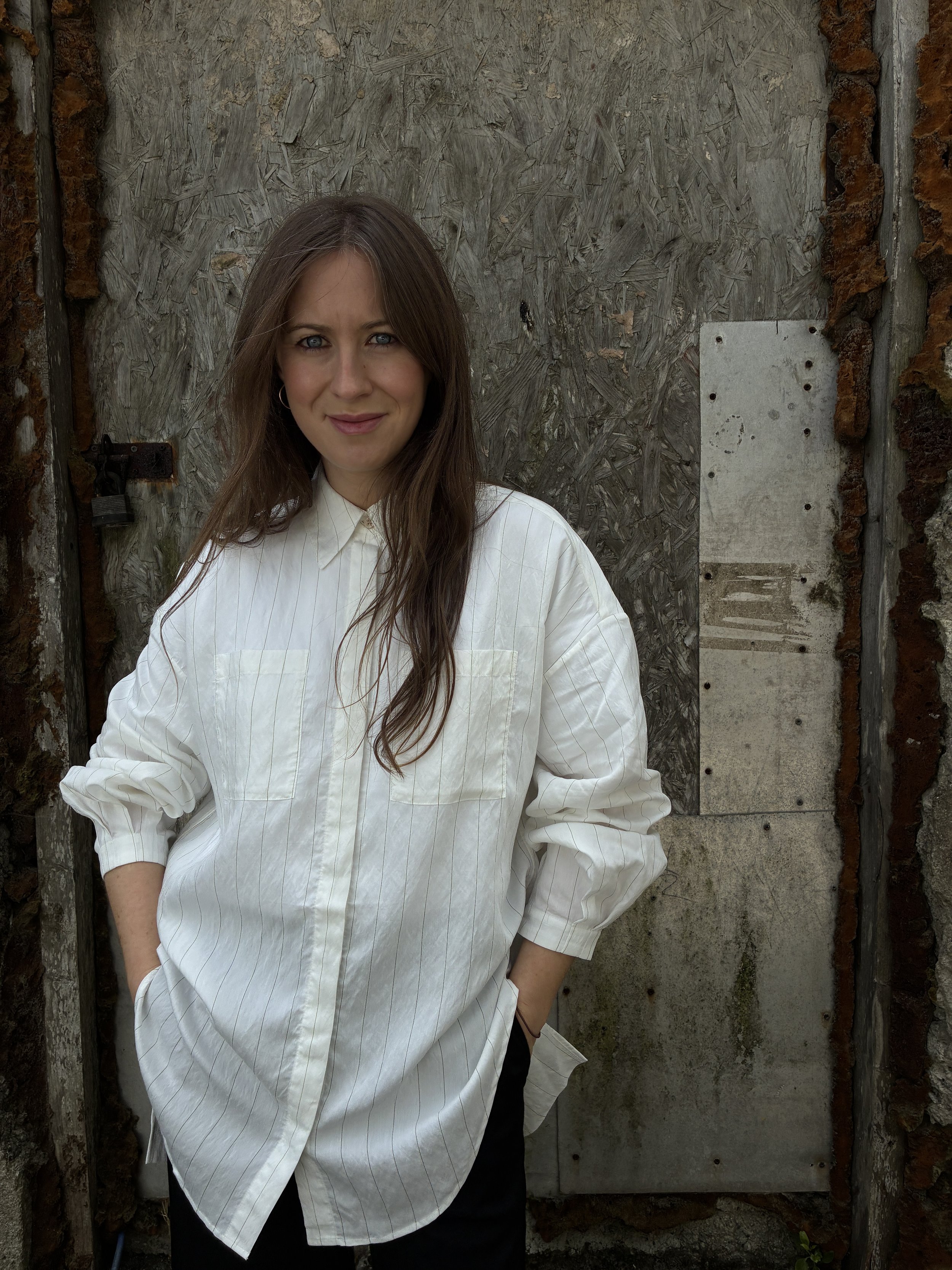 Woman in front of wall wearing 1st PAT-RN Woman Modula Shirt in  Tailored Stripes with hands in pockets