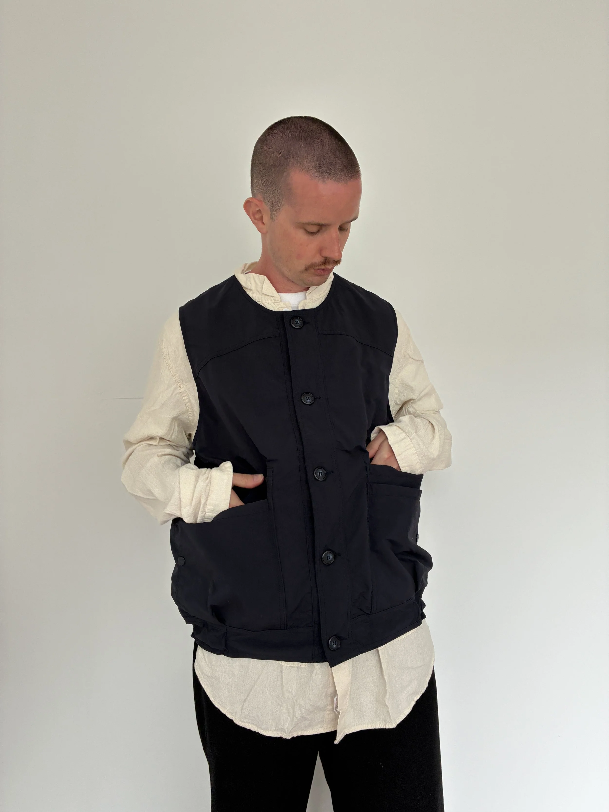 Man wearing Navy Sassafras Overgrown Hiker Vest  with hands in pockets