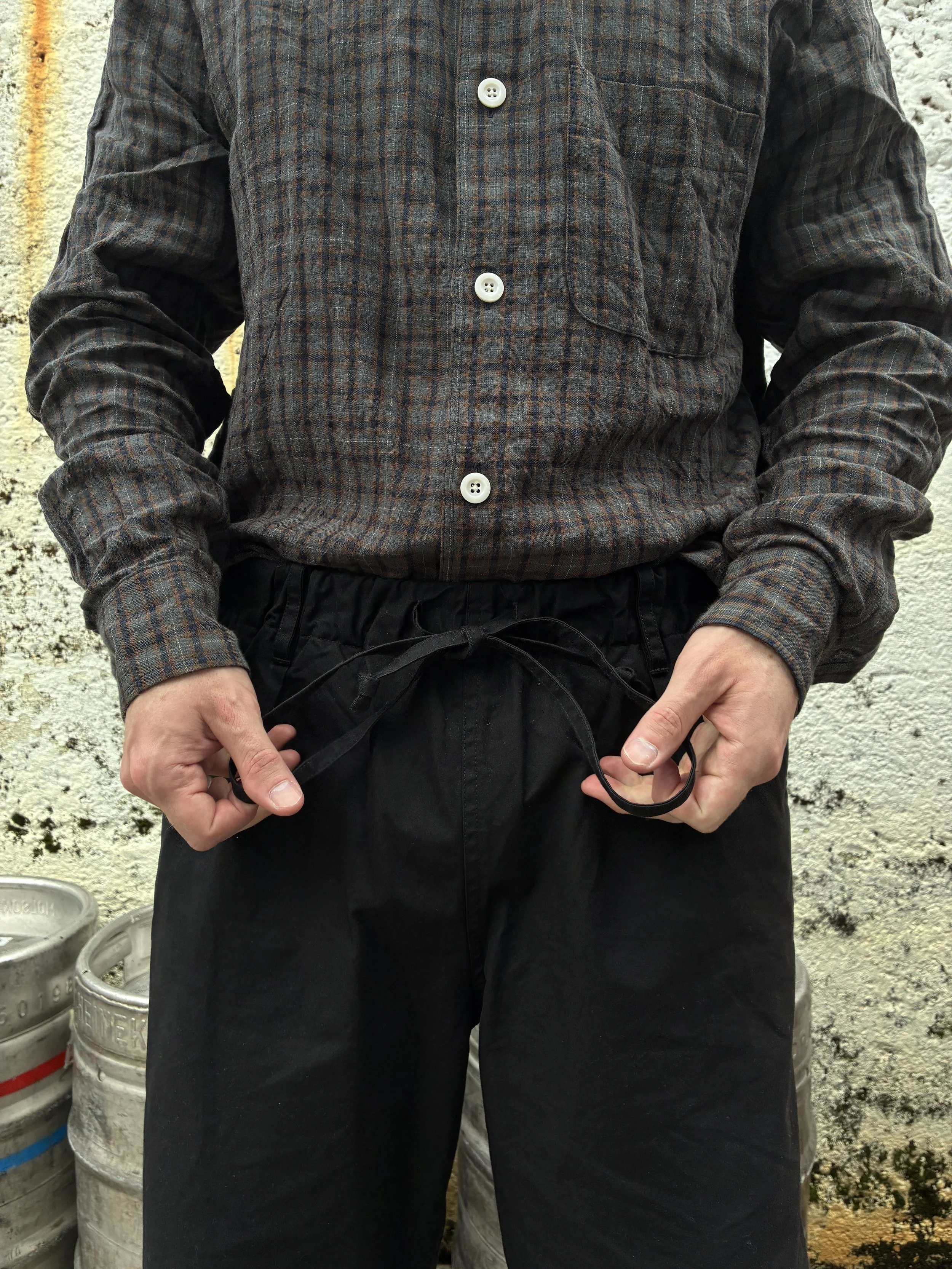 Closeup of Man tying waist of Conkers Rambler Black Waxed Cotton Trousers