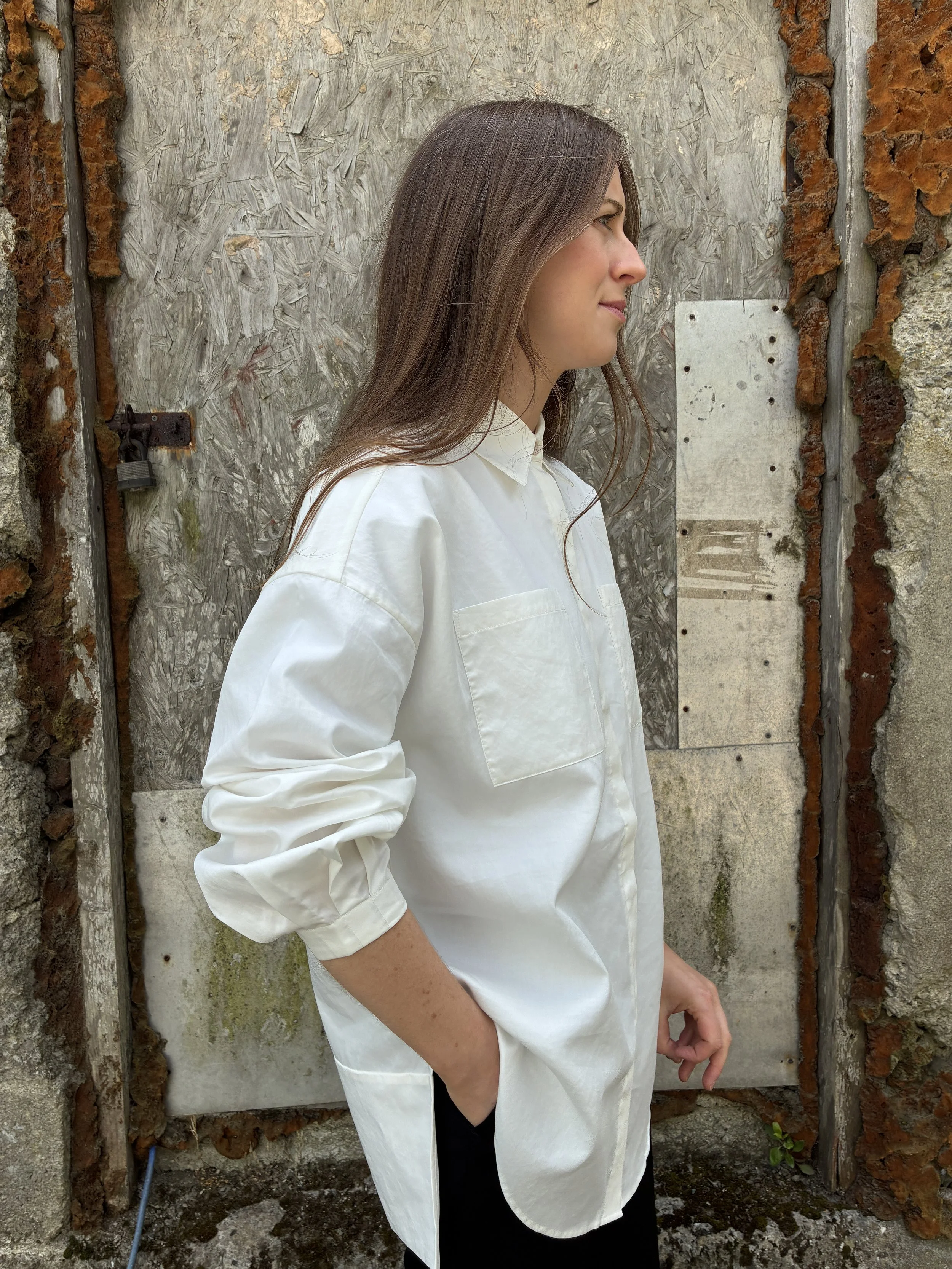 Side of Woman in front of wall wearing White 1st PAT-RN Woman Modula Shirt