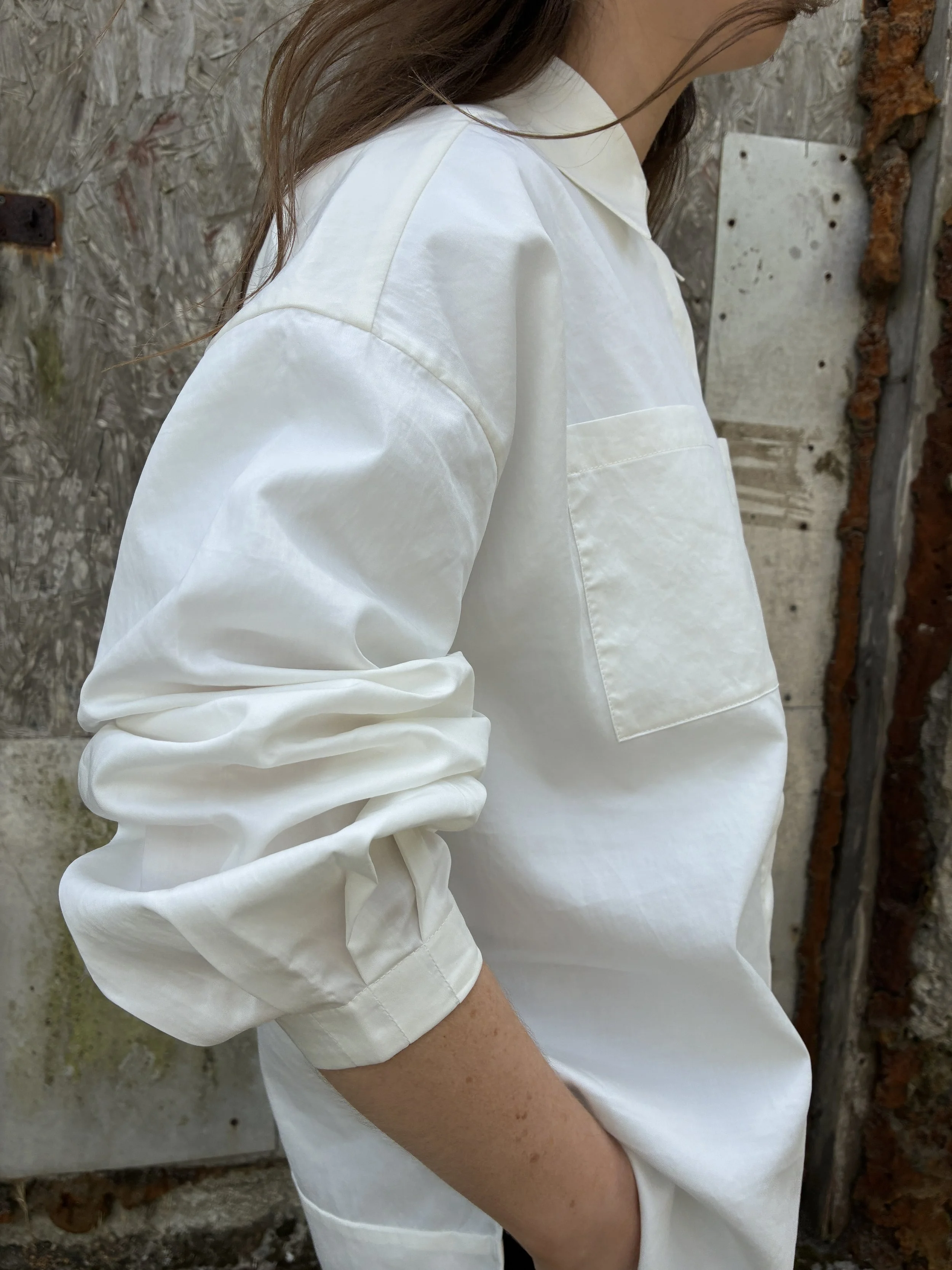 Closeup of side of Woman in front of wall wearing White 1st PAT-RN Woman Modula Shirt