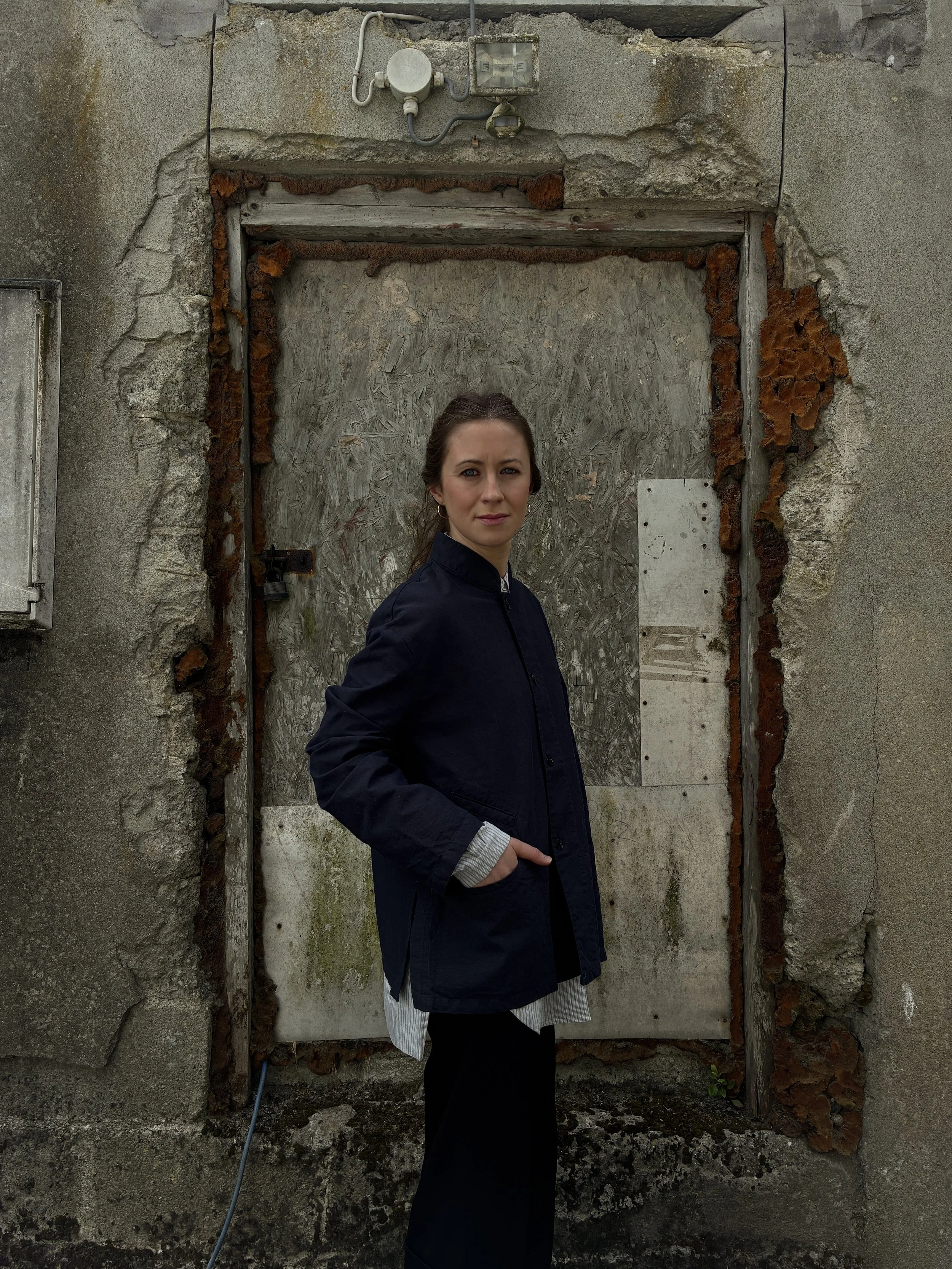 Woman in front of wall wearing Navy 1st PAT-RN Woman Rei Jacket