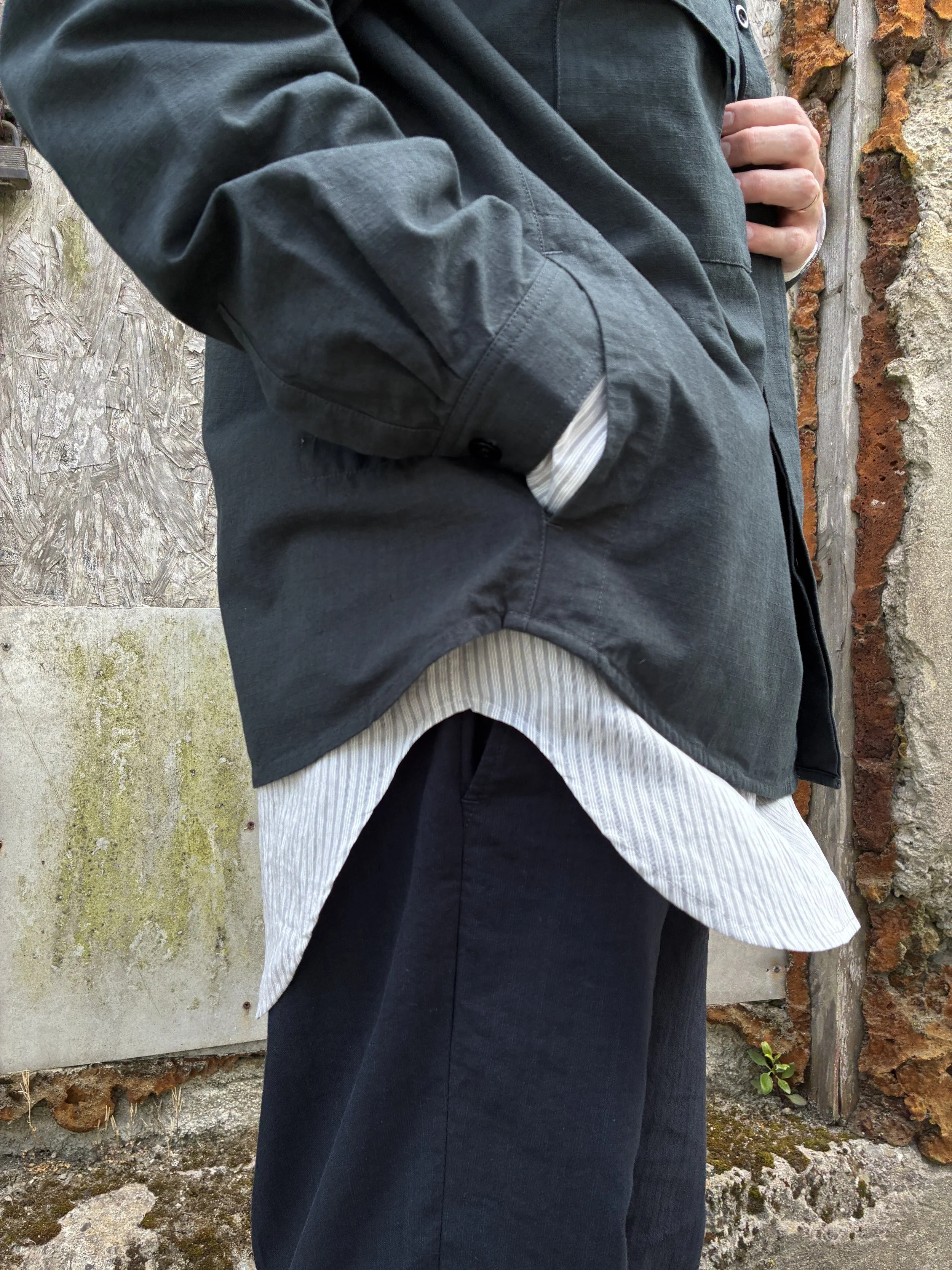 Closeup of side of Man in front of wall wearing 1st PAT-RN Sumatra Charcoal Overshirt