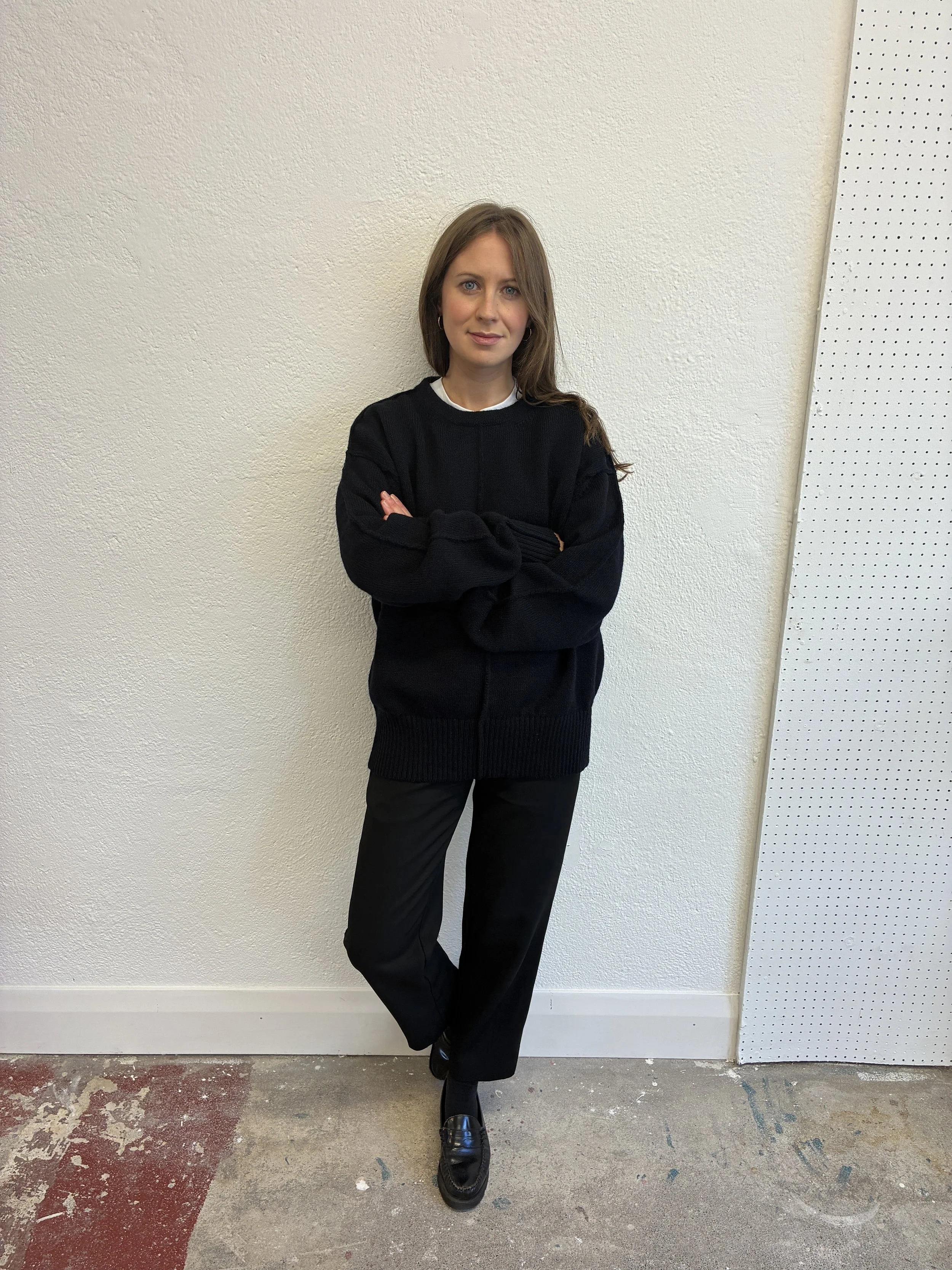 Woman wearing the Navy Tender Co Type 719 Butterfly Jumper in front of wall