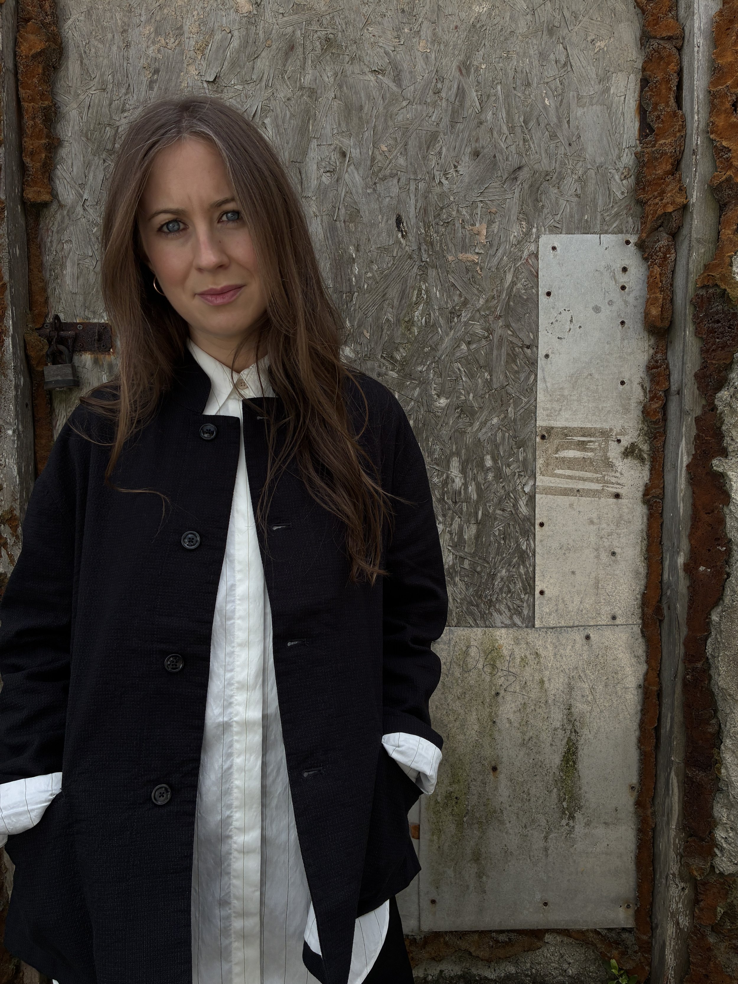 Woman in front of wall wearing Charcoal 1st PAT-RN Woman Rei Jacket with hands in pockets
