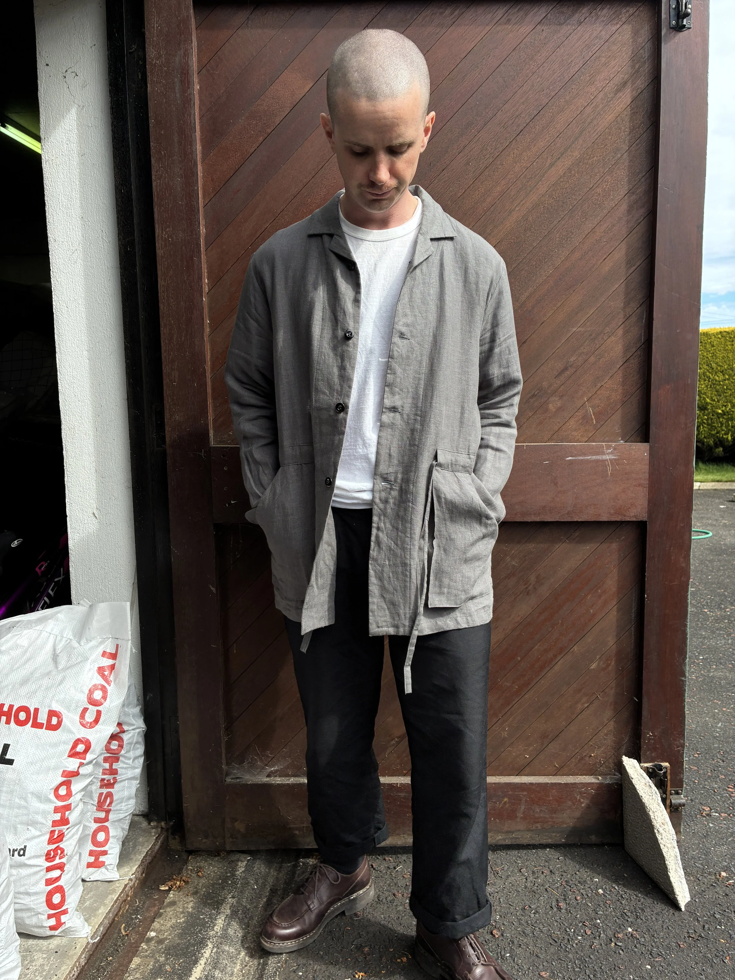 Man in front of wooden door wearing Limited Edition Frank Leder Grey LINDWURM Linen Cardigan over white tshirt
