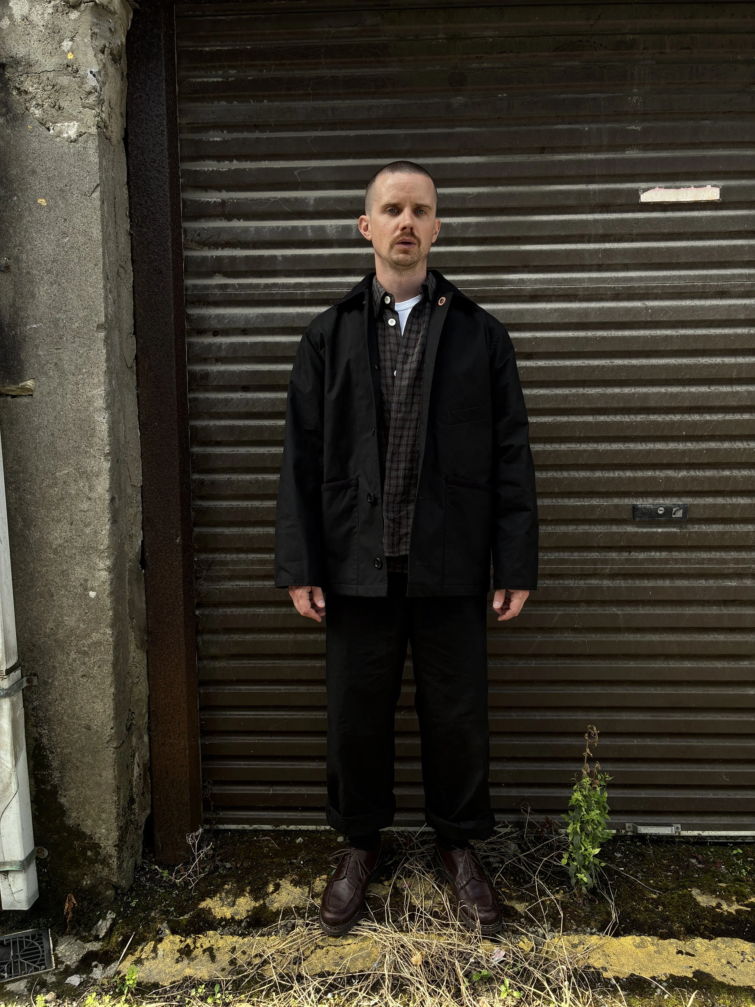 Man wearing Black Conkers Blanket Jacket in front of shutters