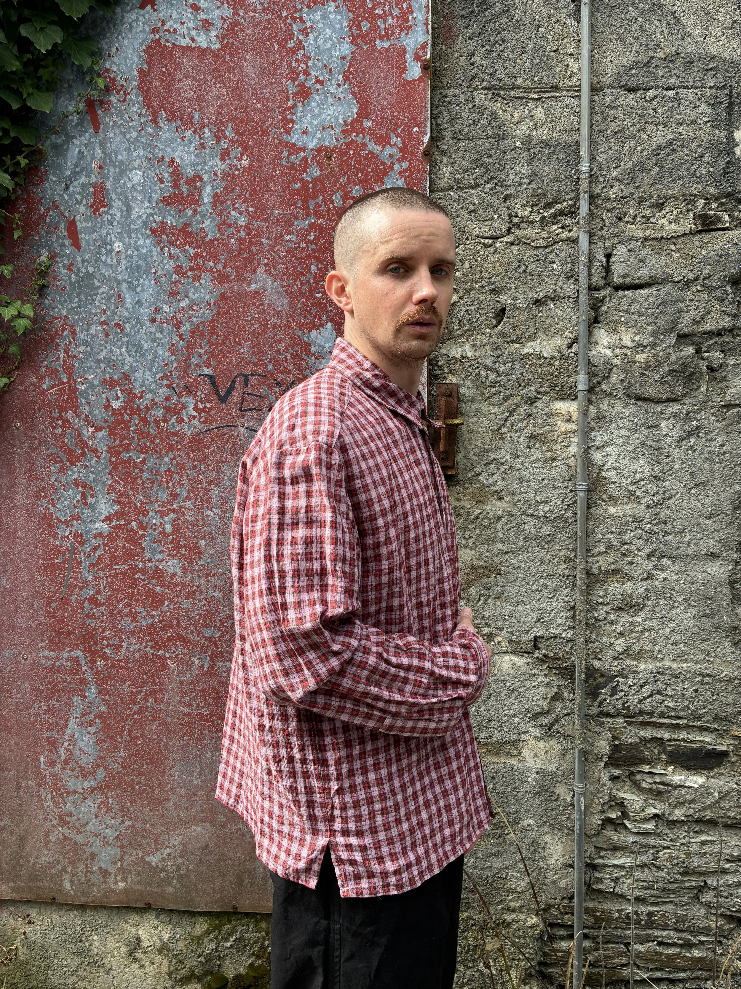 Side of man wearing Conkers Sunrise Relaxed Farmer Shirt in front of red wall