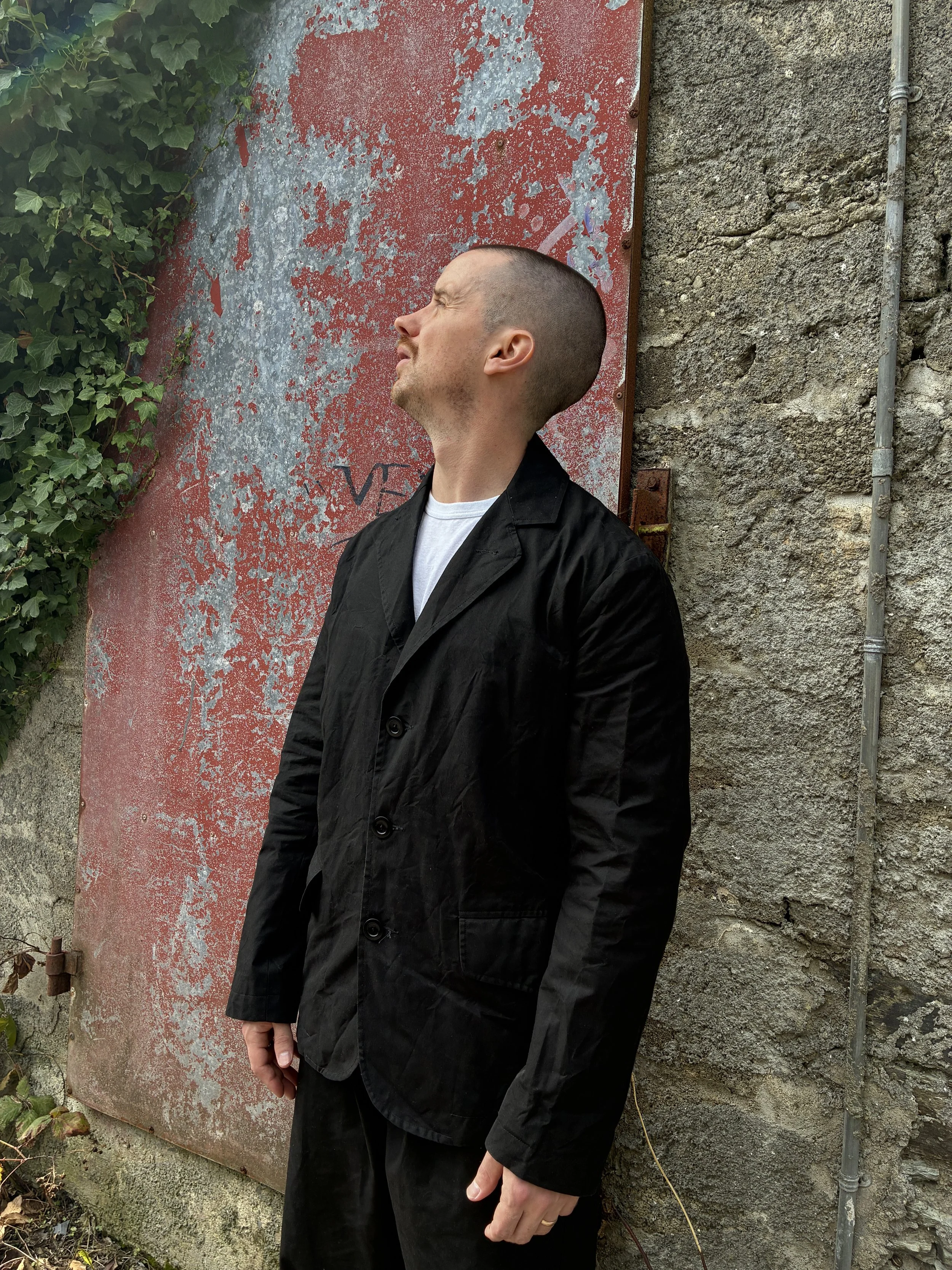 Man in front of red wall outside wearing Black Conkers Rambler Blazer