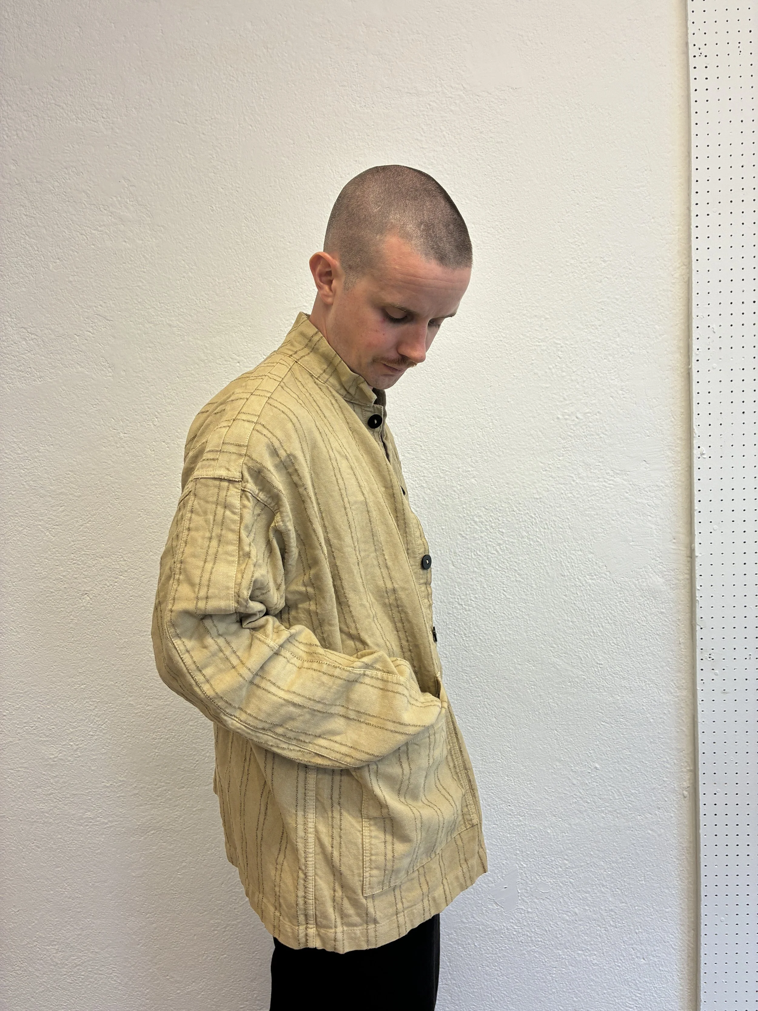 Man wearing  Drab Weld Tender Co Type 485 Isosceles Shirt in front of white wall looking down