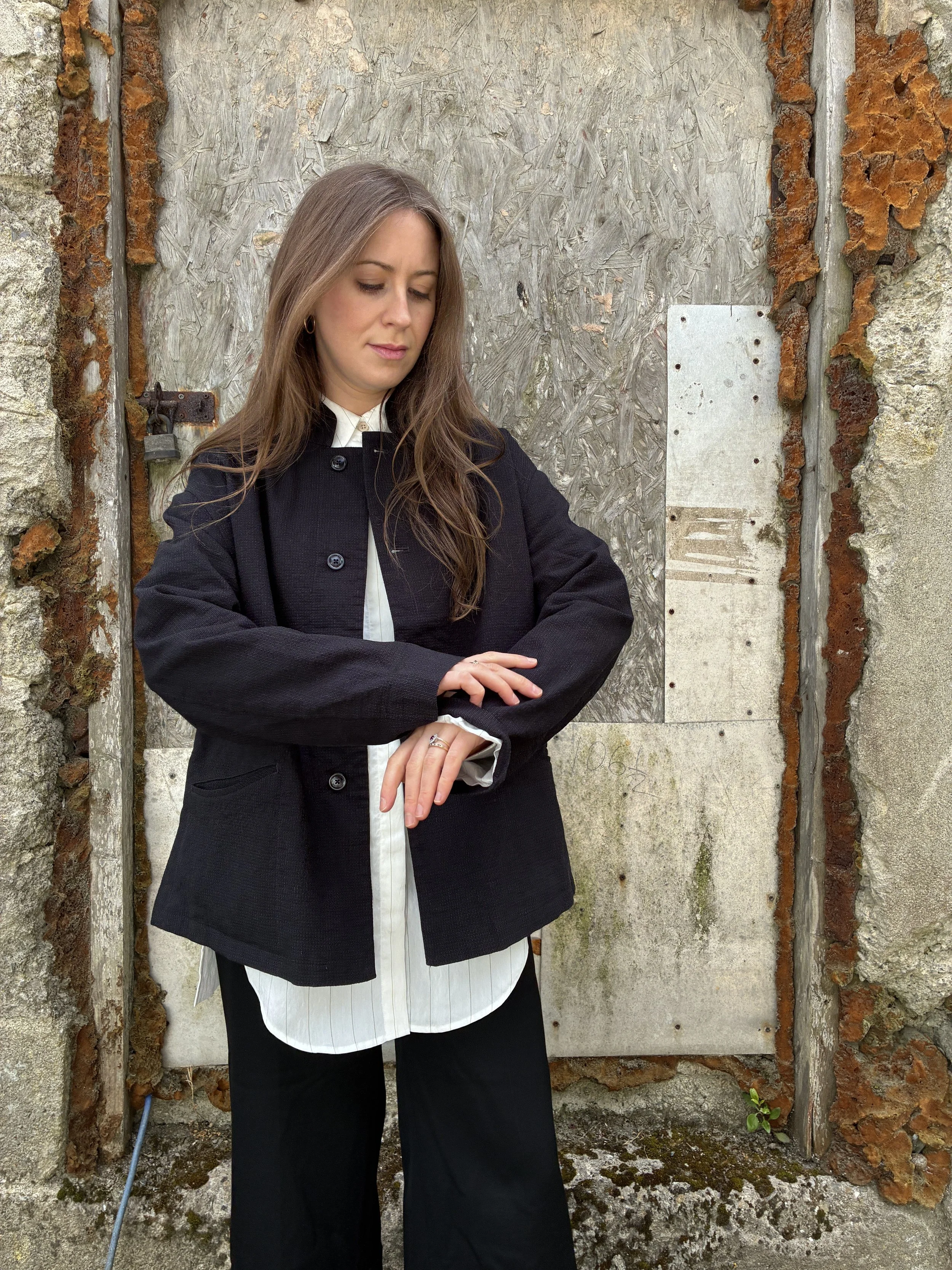Woman in front of wall wearing Charcoal 1st PAT-RN Woman Rei Jacket pulling up sleeve