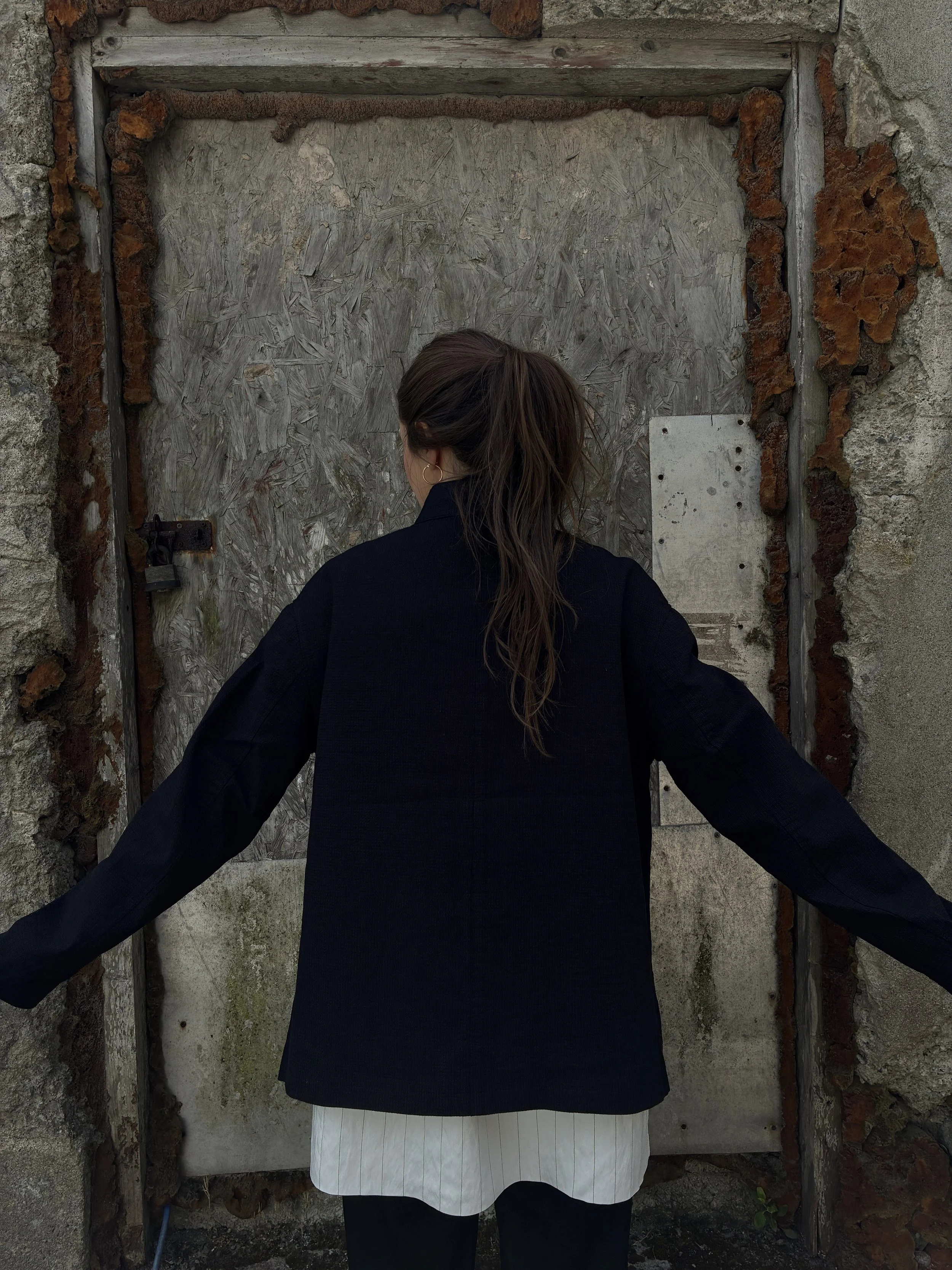 Back of Woman in front of wall wearing Charcoal 1st PAT-RN Woman Rei Jacket