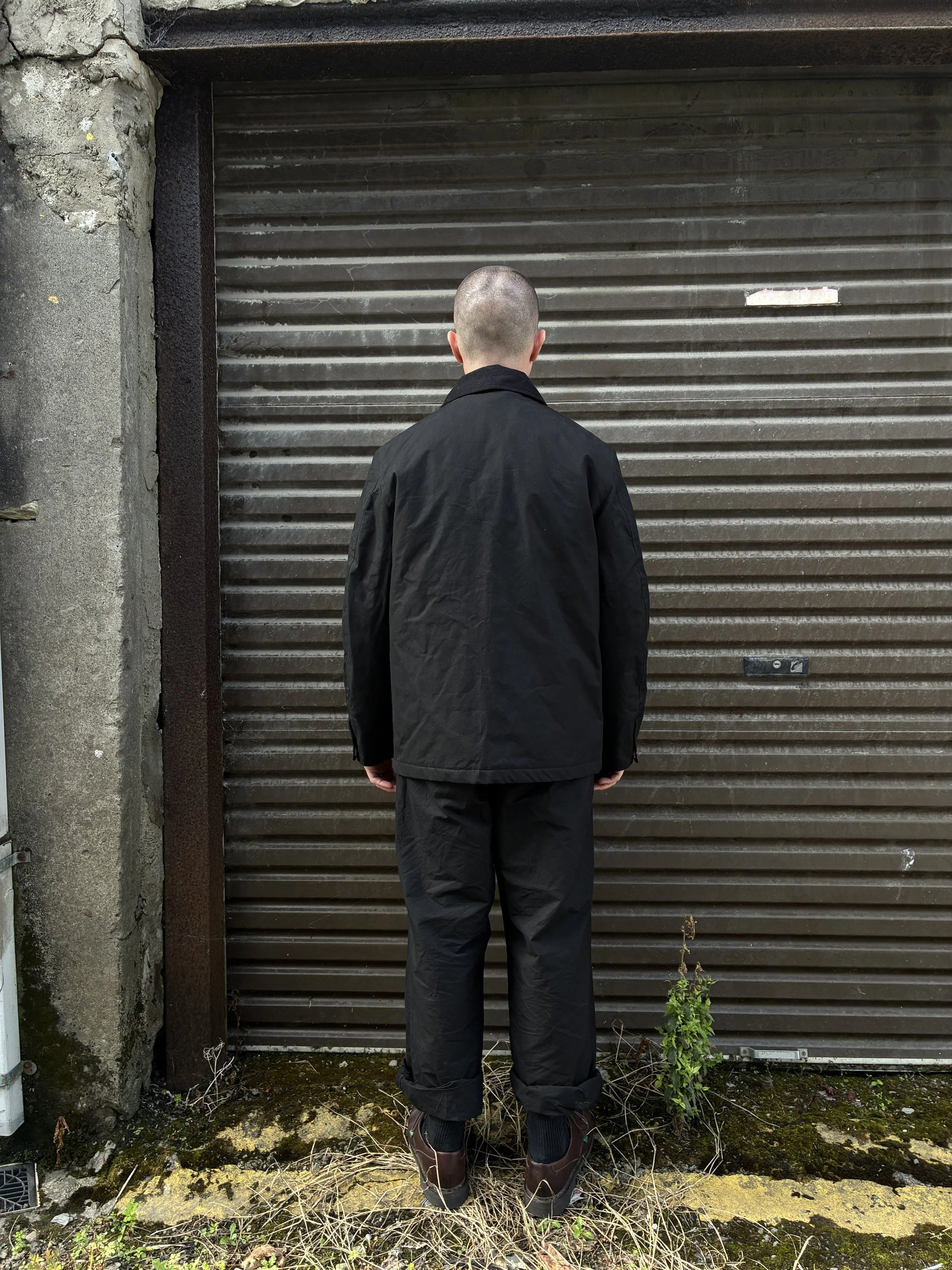 Back of Man wearing Black Conkers Blanket Jacket in front of shutters