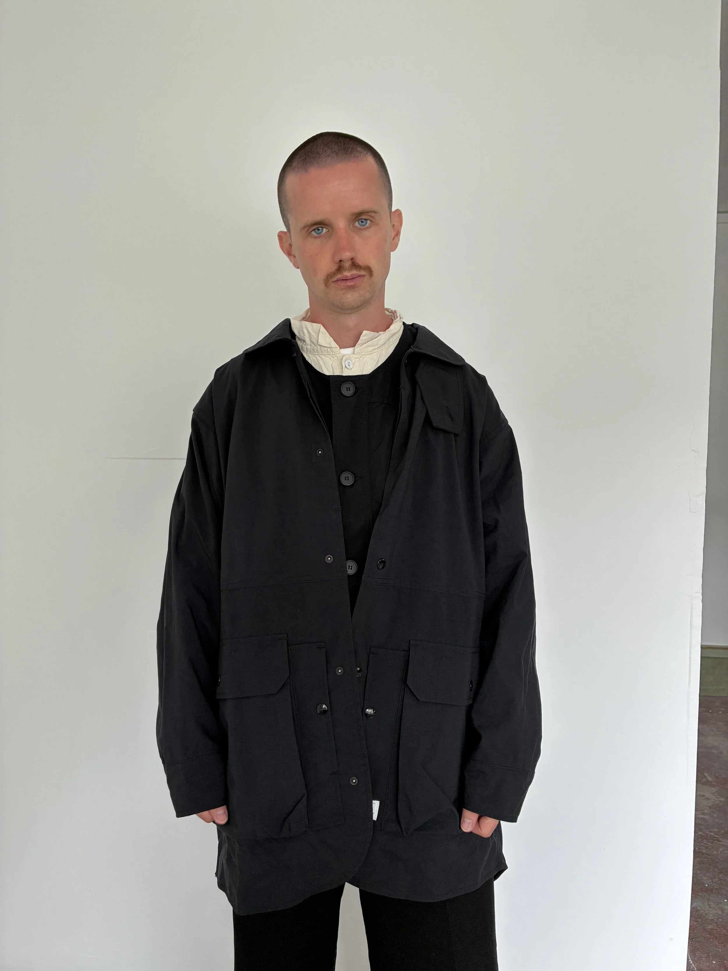 Man wearing Black Sassafras Cultivator Coat inside room